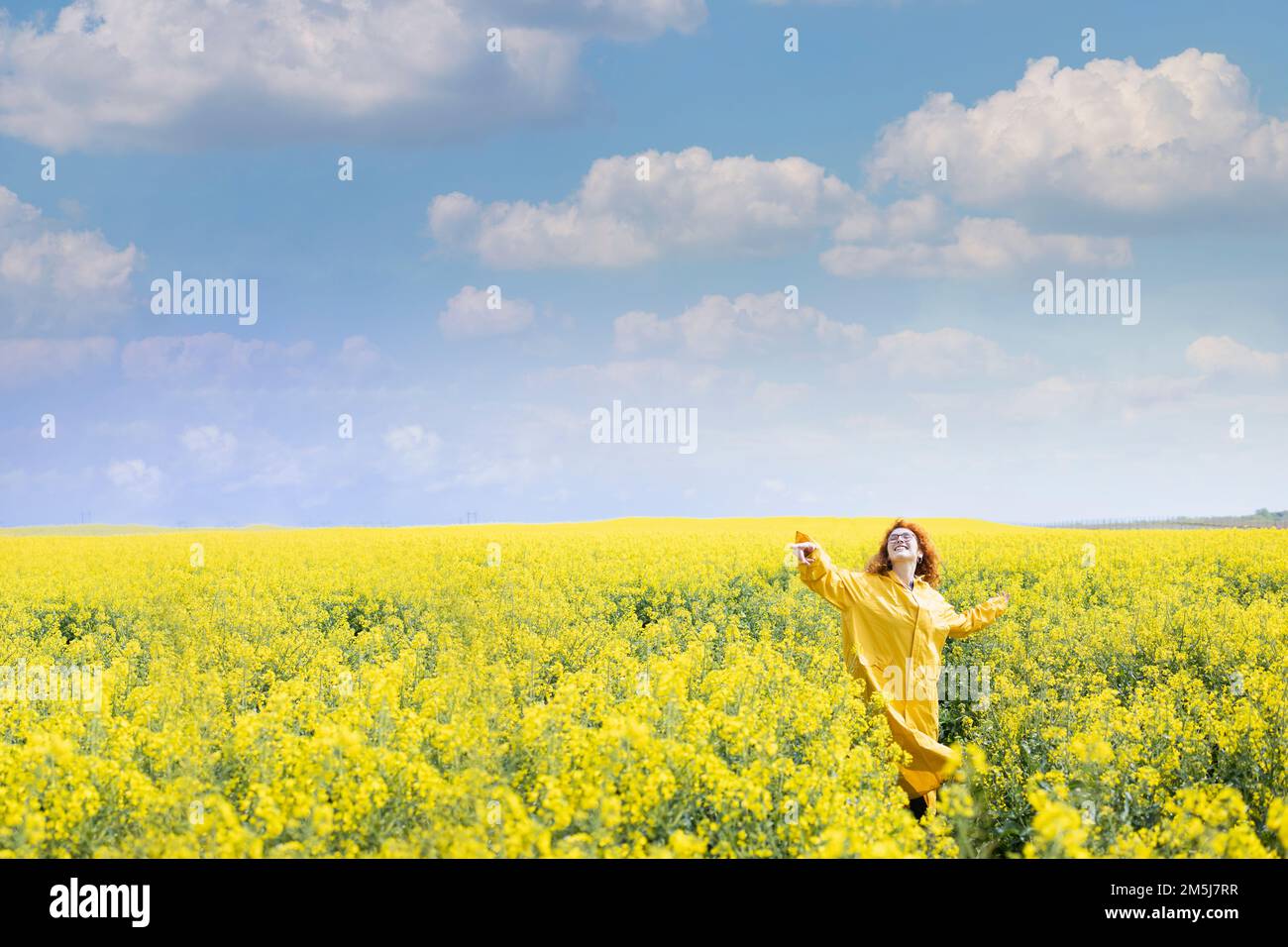 Eine Frau, die am Frühlingstag auf dem Feld tanzt und eine positive Einstellung ausdrückt Stockfoto