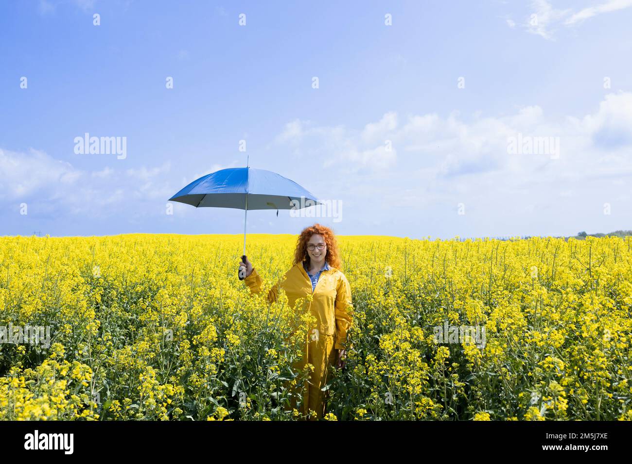 Eine Frau, die einen Regenschirm in einem gelben Feld hält Stockfoto