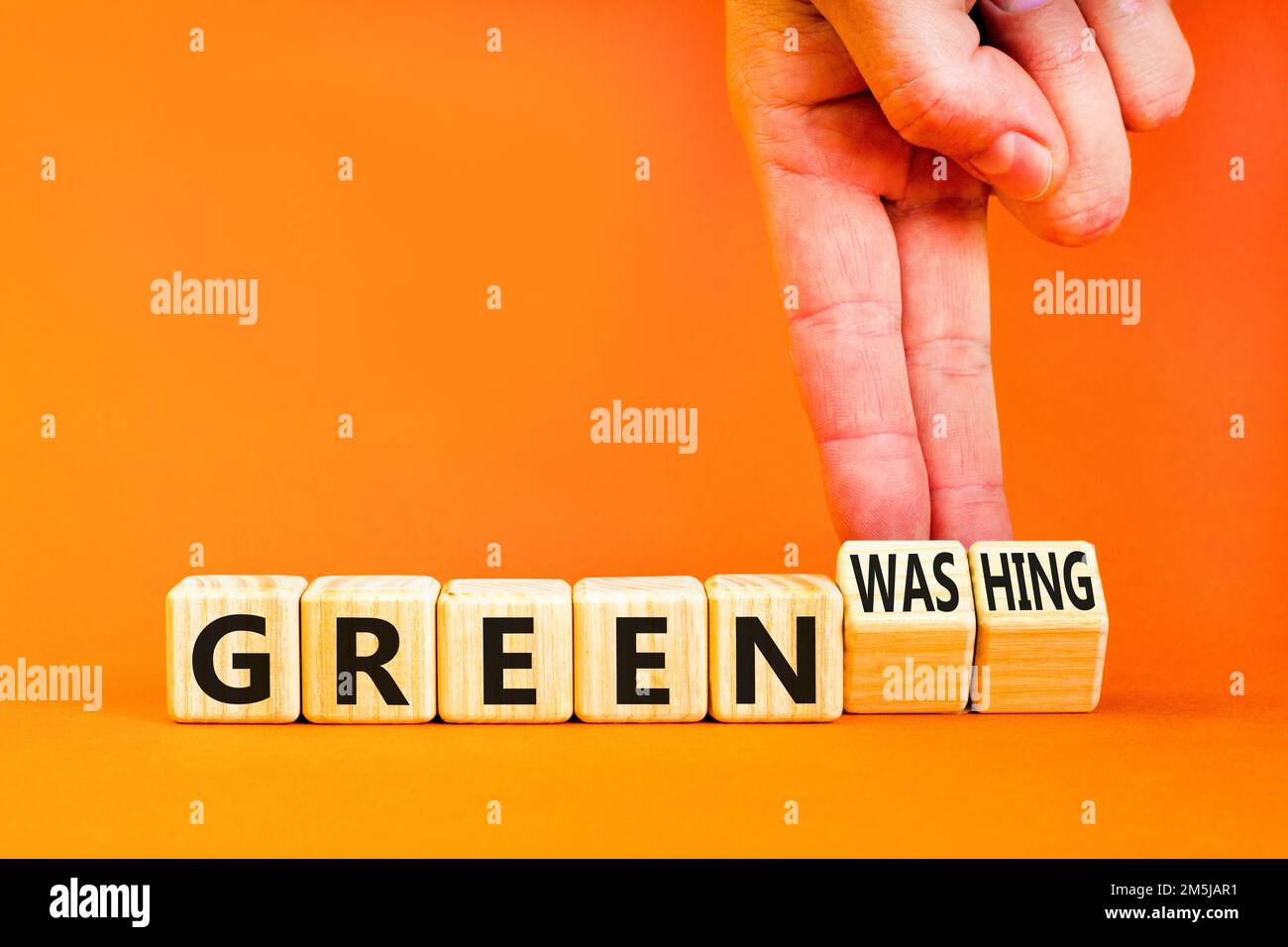 Grünes oder grünes Waschsymbol. Konzeptworte Grün und Greenwashing auf Holzwürfeln. Geschäftsmann Hand. Schöne orange Tisch orange Hintergrund. Bus Stockfoto