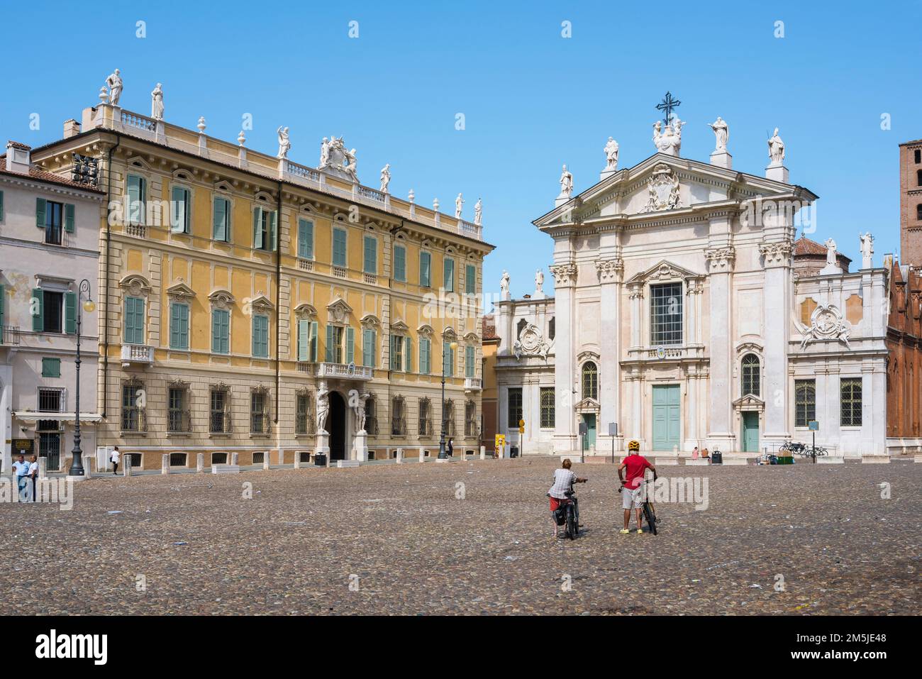 Radurlaub, Blick im Sommer auf ein erfahrenes Fahrradpaar, das auf der Piazza Sordello in Mantua pausiert, um die barocke Fassade des Doms in Italien zu erkunden Stockfoto