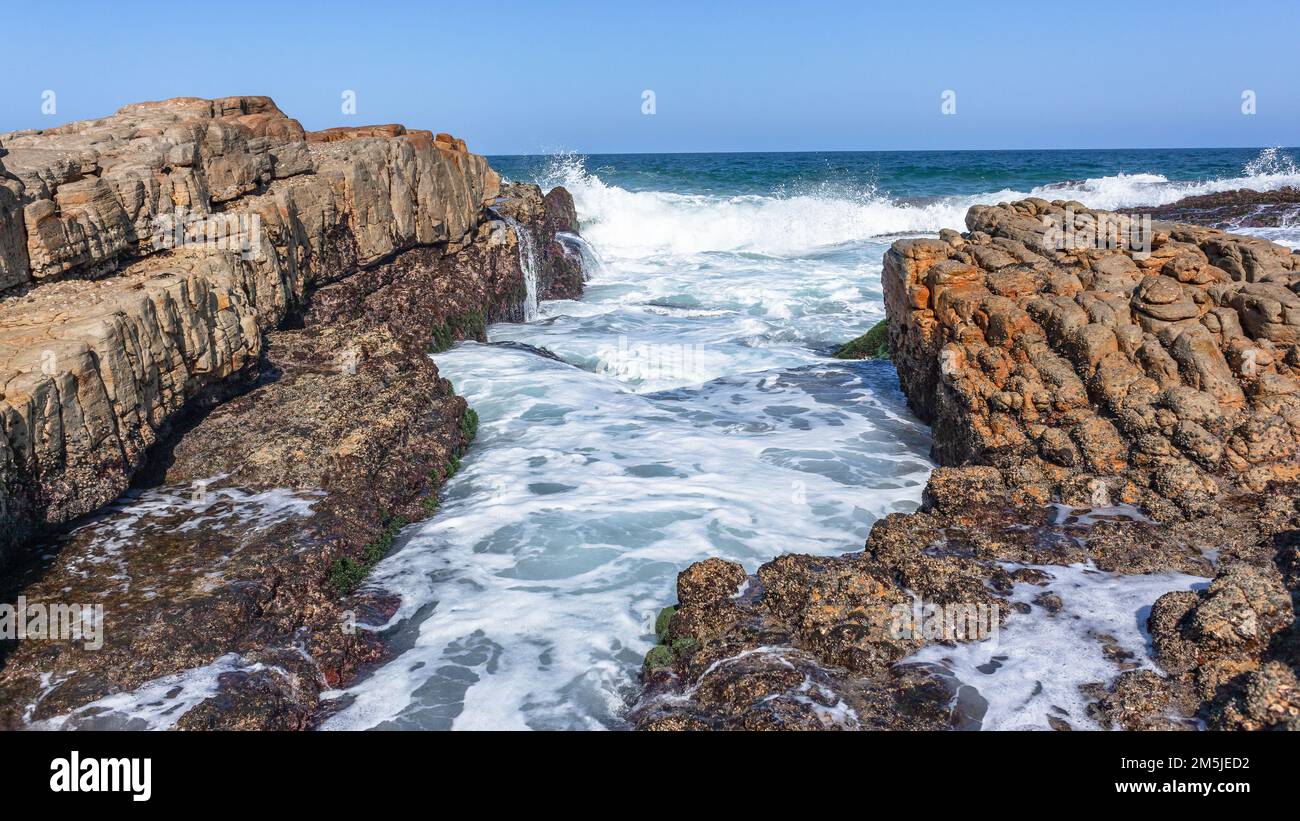 Felsige Küste Meerwasser rauscht in Felsschächten, Meerwasserspülung Wassersprühkraft entlang der Strandlandschaft. Stockfoto