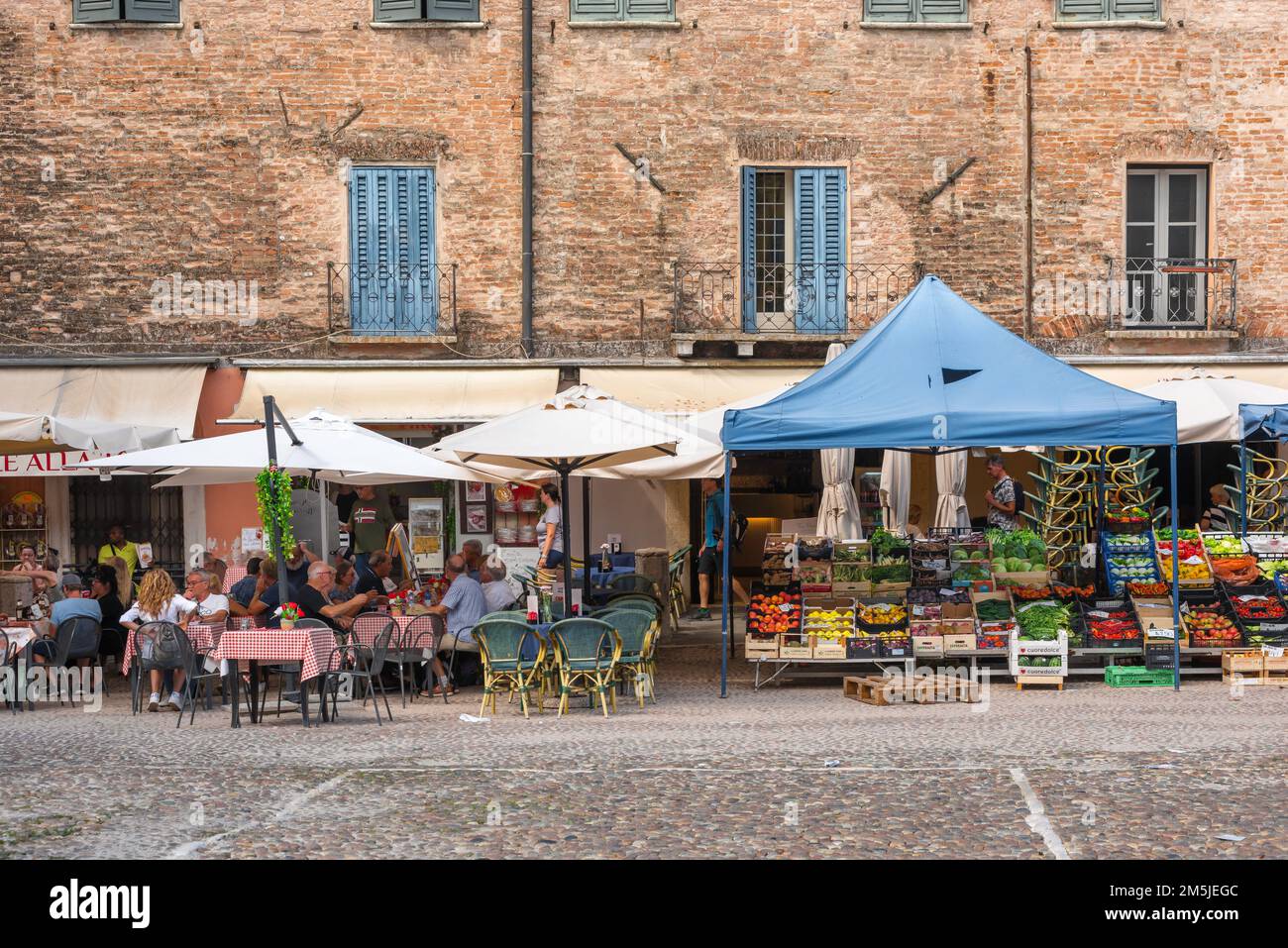 Italien Street Cafe, im Sommer Blick auf die Menschen, die an Cafetstischen auf einem malerischen alten Marktplatz sitzen, Piazza Sordello, Mantua (Mantova), Lombardei, Italien Stockfoto