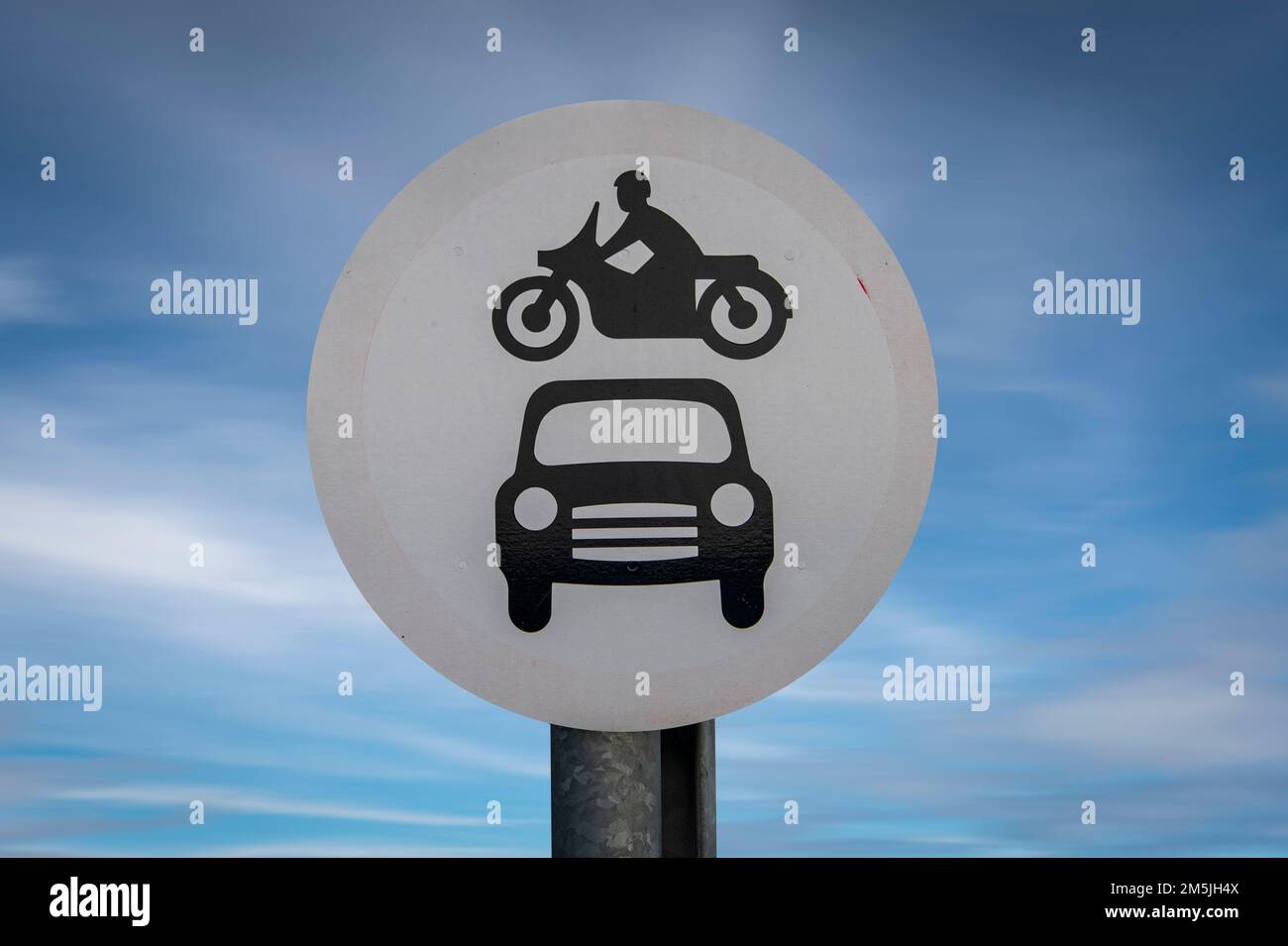 Verblasstes Straßenschild, Motorfahrzeuge verboten, mit einem Motorrad über dem Auto vor blauem Himmel Stockfoto