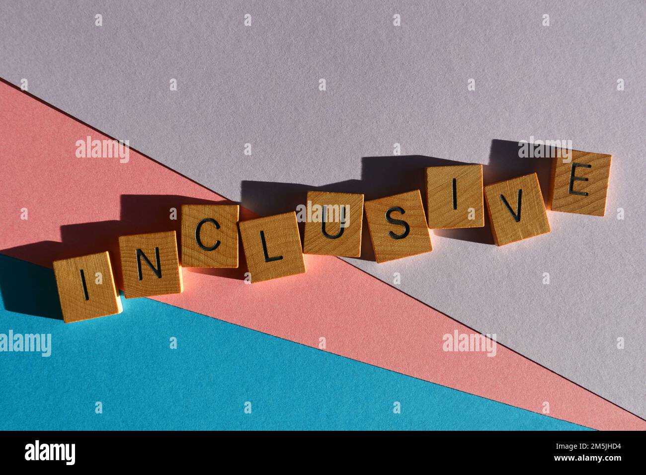 Inklusive Wort in hölzernen Buchstaben isoliert auf pinkfarbenem, lila und blauem Hintergrund Stockfoto