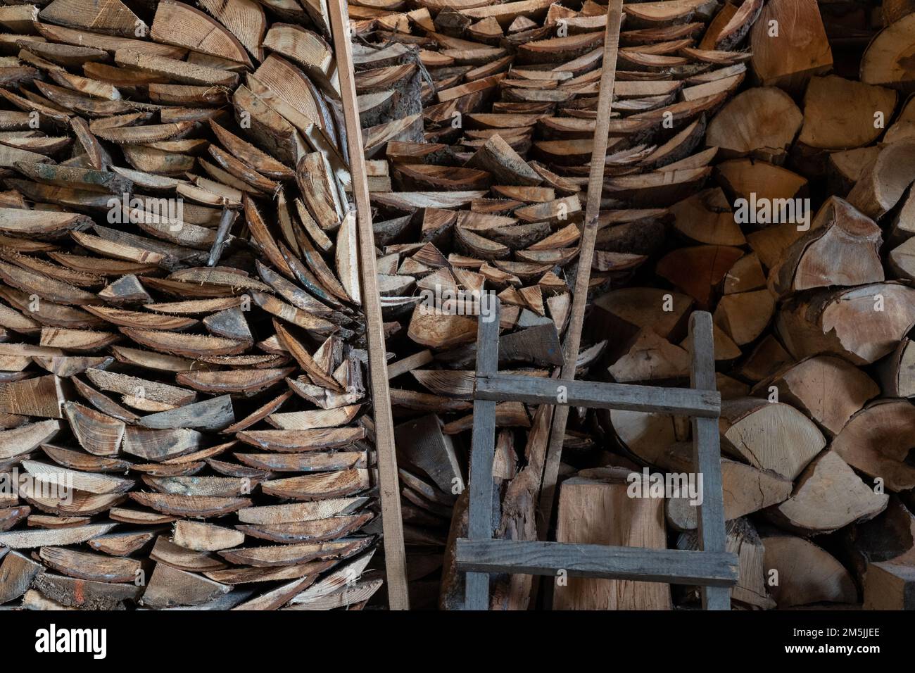 Der Bestand an Buchenholzstücken, die im Haushalt zur Erwärmung im Winter gelagert werden, schafft attraktive visuelle Muster und eine entspannende Komposition Stockfoto