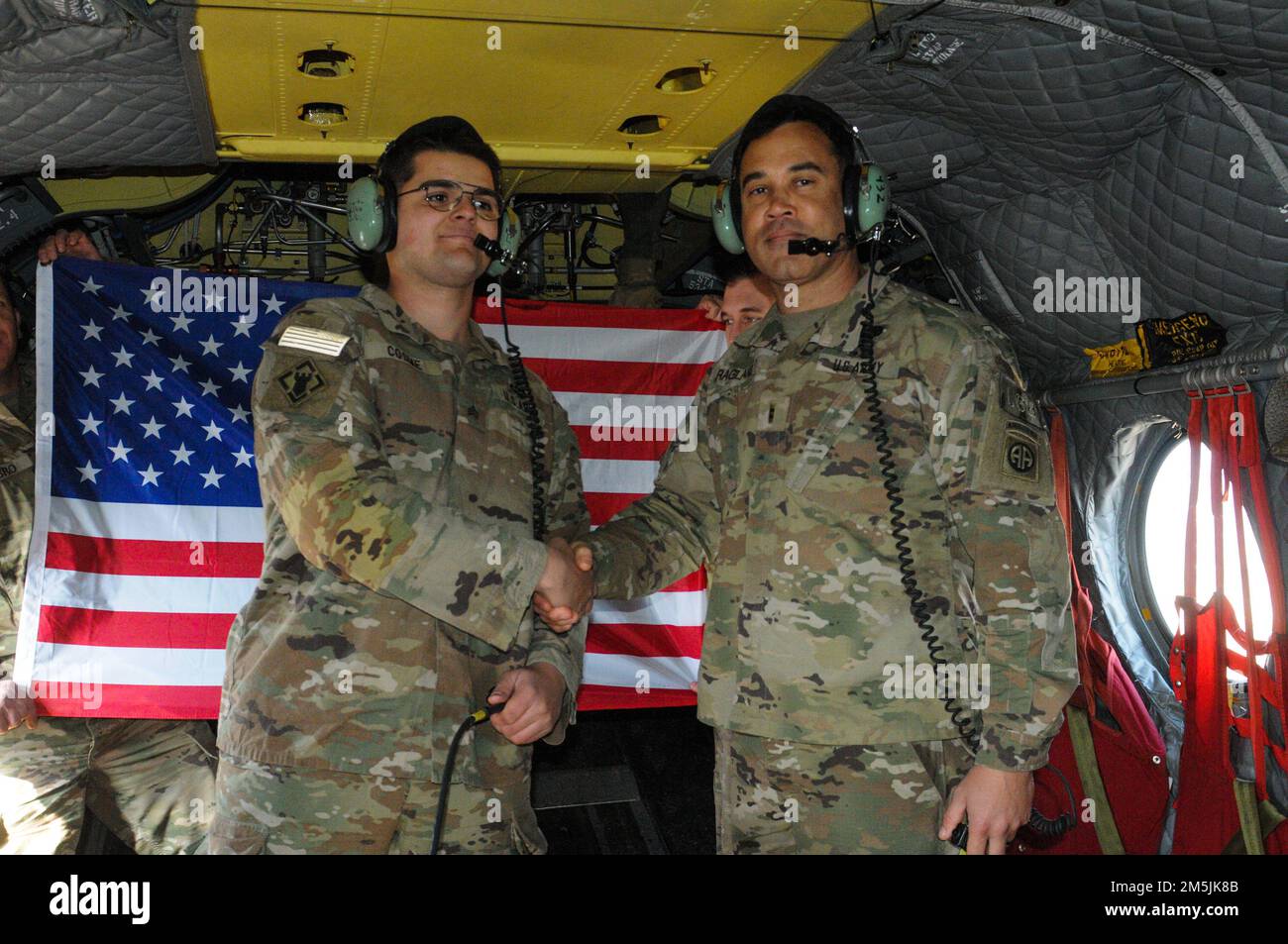 (Links) USA Army Sgt. Isaiah Cosme meldet sich wieder in einem Chinook-Hubschrauber während seiner Einsätze in Polen, März 19. Sgt. COSME stammt aus Westbrook, Maine, und hat den Westbrook High School Class 2016 abgeschlossen. Stockfoto