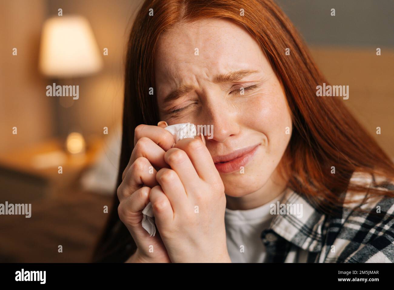 Nahaufnahme von trauriger junger Frau, die weint und Tränen mit Taschentüchern abwischte, an einer schlechten Beziehung litt, sich einsam fühlte, allein im Bett saß Stockfoto