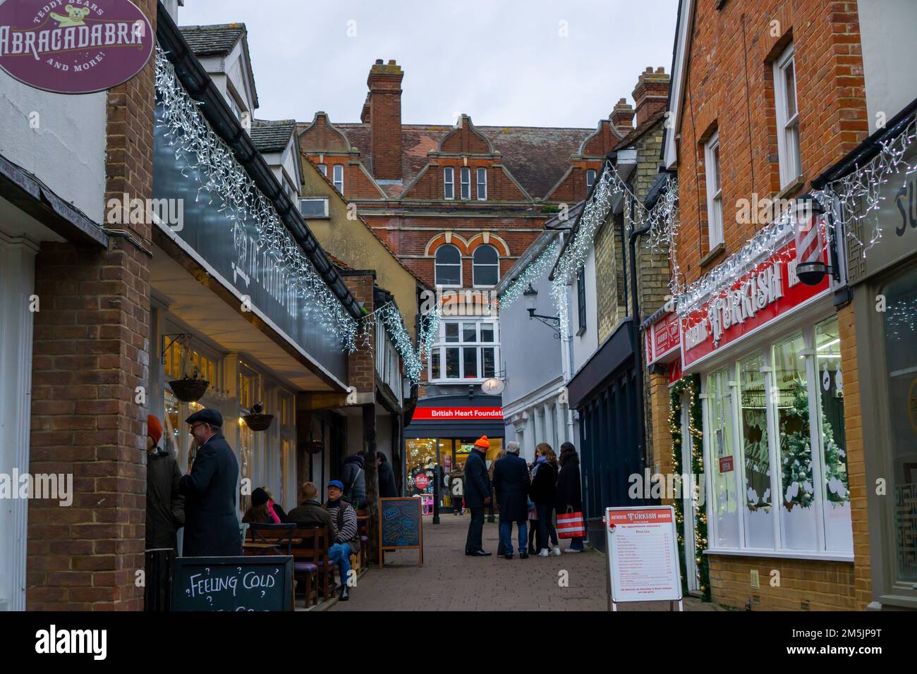 Menschen in einem kleinen Einkaufsviertel mit Weihnachtsdekorationen in Saffron Walden, Essex, Großbritannien Stockfoto