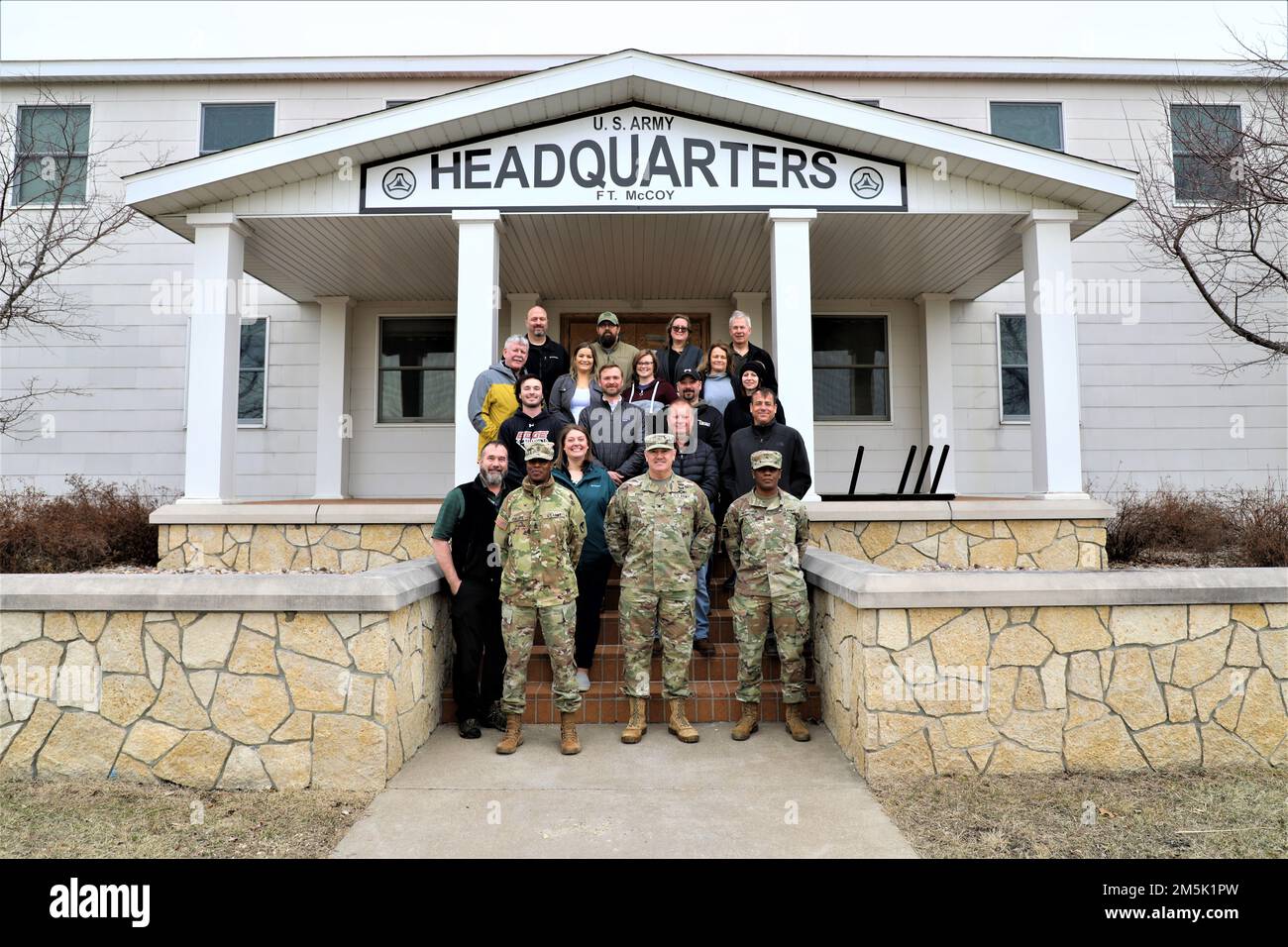 Teilnehmer an einer Veranstaltung zum Engagement der Community Leader für ein Foto vom 21. März 2022 vor dem Hauptquartier von Garrison in Fort McCoy, Wisconsin. Mehr als ein Dutzend Gemeindeführer aus Tomah, Sparta, Black River Falls, La Crosse und anderen nahegelegenen Gemeinden haben sich in Fort McCoy versammelt, um die Mission der Post aus erster Hand zu sehen. Während ihres Besuchs erhielten die Führer der Gemeinde eine Fahrt durch die Anlage und machten Halt an der Combined Arms Collective Training Facility in South Post, Fort McCoy Commemorative Area, Fort McCoy Simulations Training Complex im 200. Block im Kantonment Area, Garr Stockfoto