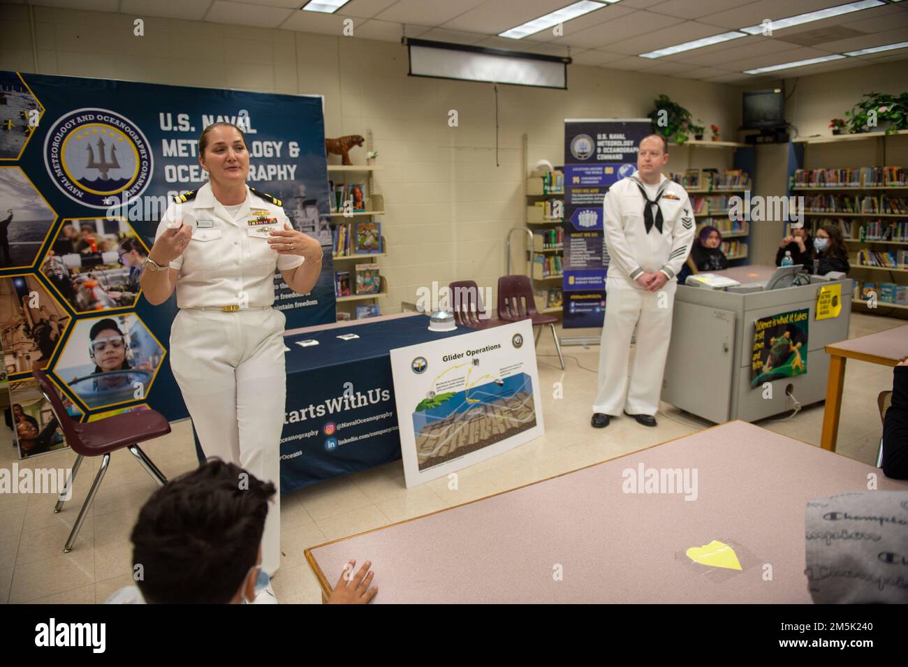 TAMPA, Florida (22. März 2022) LT. Nicole Stegall und Aerographer's Mate 1. Klasse Christopher Brunner präsentieren Schulkindern zur Tampa Bay Navy Week. Die Navy Week ist eine jährliche Reihe von Veranstaltungen, die das ganze Jahr über in verschiedenen US-amerikanischen Städten stattfinden, in denen die Marine nicht präsent ist. Sie bietet den Bürgern die Möglichkeit, mit Seeleuten zu interagieren und mehr über die Navy und ihre Fähigkeiten zu erfahren. Stockfoto