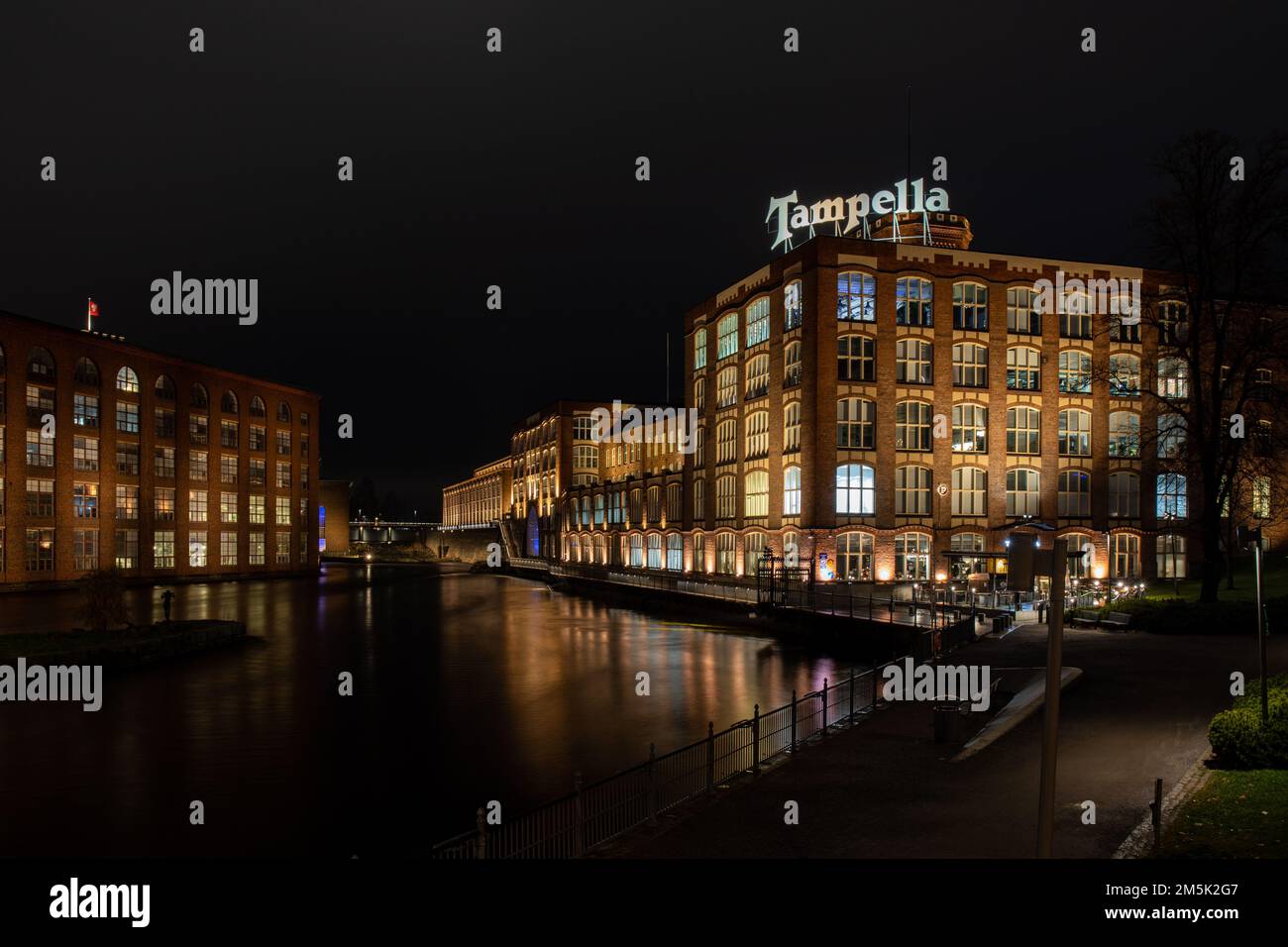 Tammerkoski radelt nach Einbruch der Dunkelheit in Tampere, Finnland, mit ehemaligen Industriegebäuden von Finlayson und Tampella Stockfoto