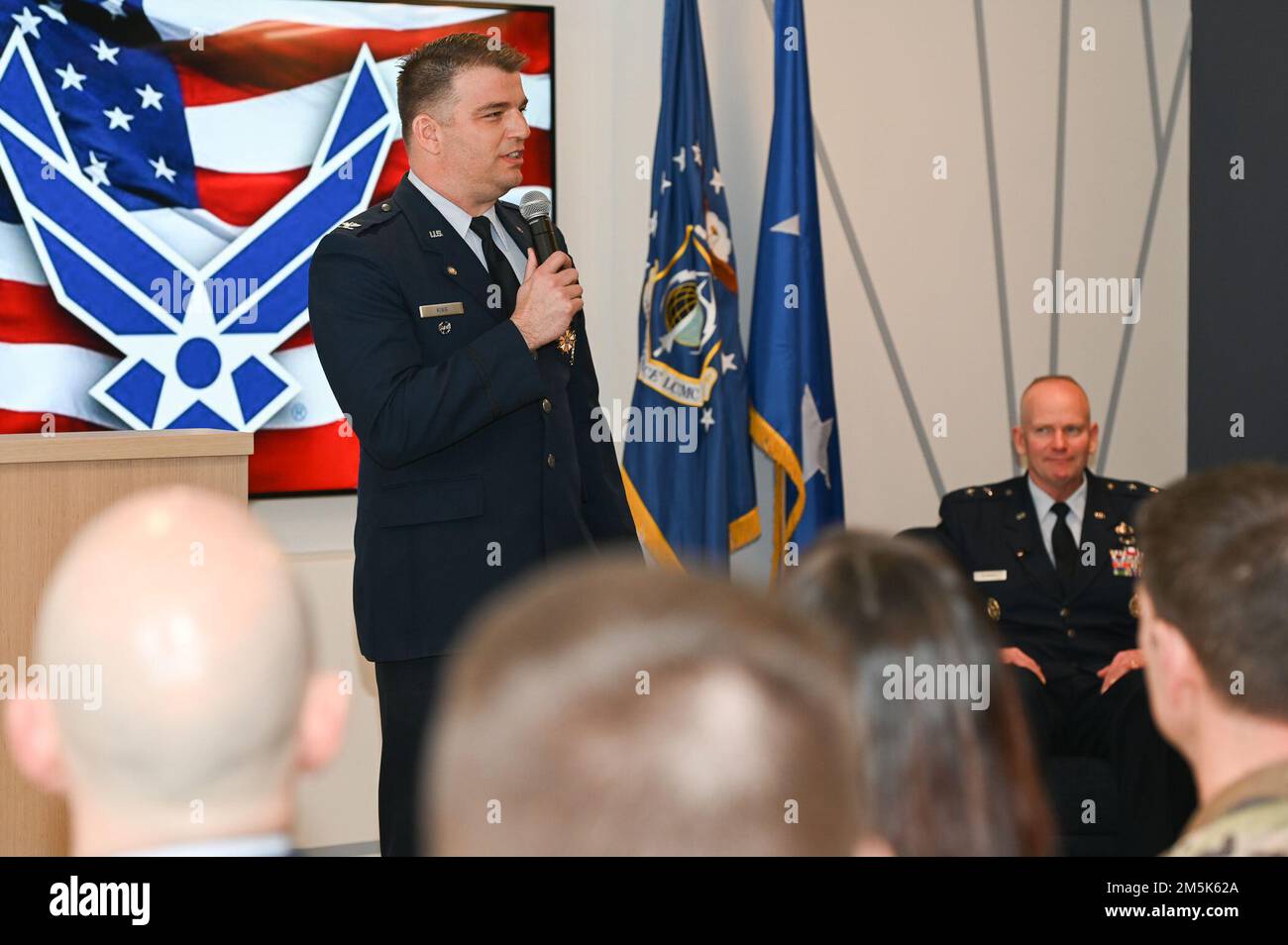 Oberst Robert King, Senior materiel Leader der Abteilung Enterprise Information Technology and Cyber Infrastructure, spricht während seiner Ruhestandsfeier im Collaborative Nerve Center, Concord, Mass., März 21, während Major General Michael Schmidt, Executive Officer des Programms Command, Control, Communications, Intelligence and Networks, und andere dabei zuschauen. King ging nach 27 Jahren Dienst bei der Air Force in den Ruhestand. Stockfoto