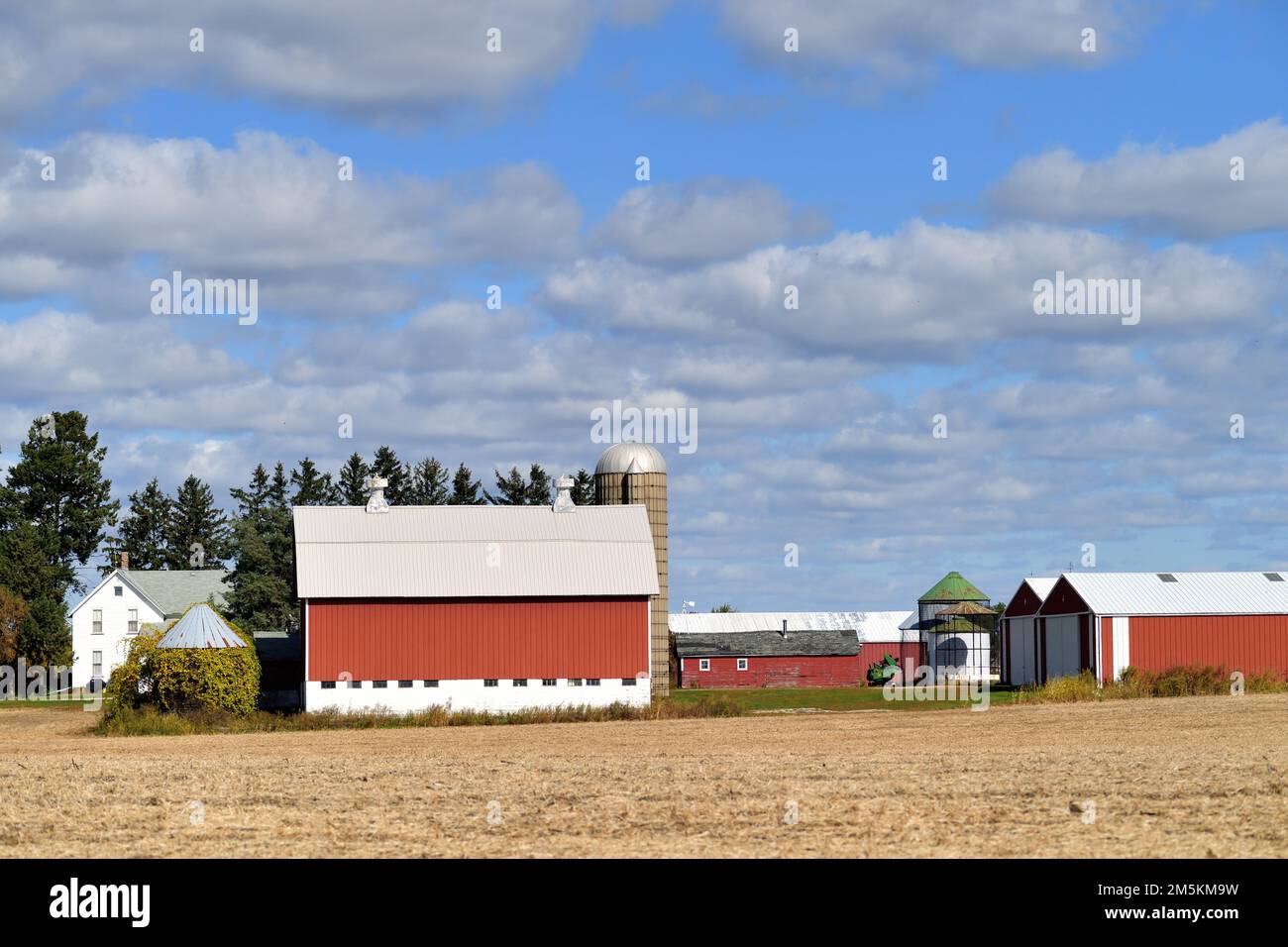 South Elgin, Illinois, USA. Eine moderne, hellrote Scheune jenseits eines Feldes mit geernteten Pflanzen an einem Herbsttag. Stockfoto