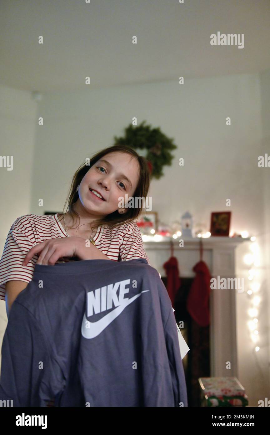 Sycamore, Illinois, USA. Ein Mädchen, das den Inhalt eines Geschenks zeigt, nachdem es am Weihnachtstag ein Paket geöffnet hat. Stockfoto