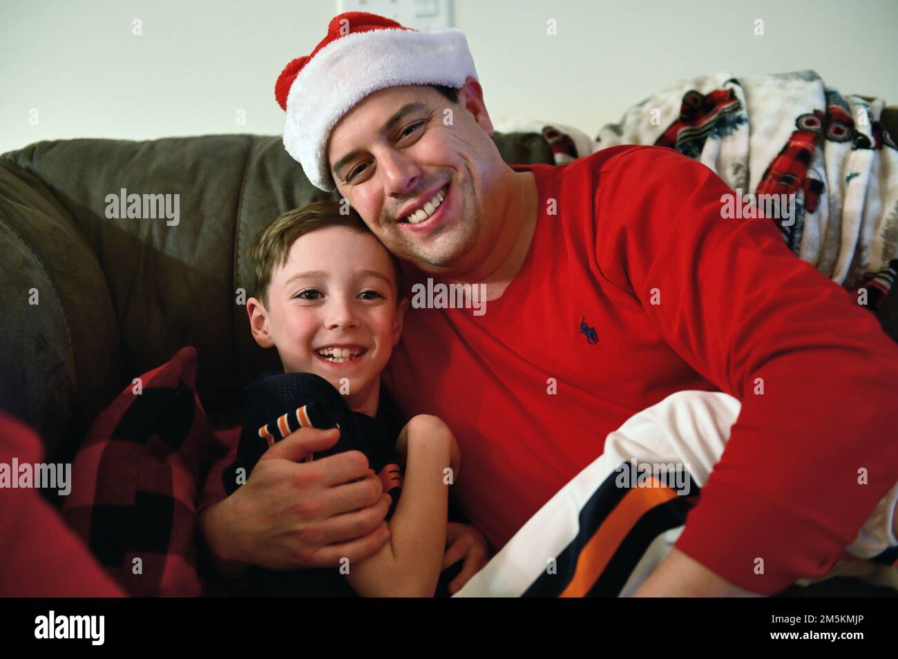 Sycamore, Illinois, USA. Vater und Sohn verbringen am ersten Weihnachtsfeiertag einen schönen Moment auf der Couch im Familienzimmer. Stockfoto