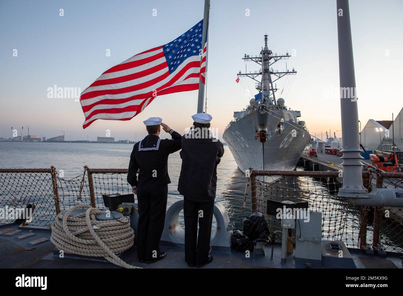 KOPENHAGEN, Dänemark (23. März 2022) — Seaman Johnathan Sacco, Left, und Gunner’s Mate Seaman Apprentice Ethan Parsons, dem Arleigh Burke-Class Guided-Missile Destroyer USS Donald Cook (DDG 75) zugeteilt, senken den Fähnrich während seines Aufenthalts im Hafen von Kopenhagen, Dänemark, mit USS The Sullivans (DDG 68) auf dem Flugdeck (23. März). Donald Cook und die Sullivans werden zum European Theatre of Operations entsandt und nehmen an einer Reihe von maritimen Aktivitäten zur Unterstützung der USA Teil Sechste Flotte und NATO-Verbündete. Stockfoto
