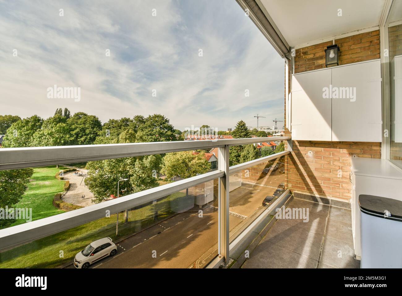 Balkon mit Blick auf die Bäume und Gebäude in der Ferne, von einem Apartmentfenster mit Blick auf die Straße Stockfoto