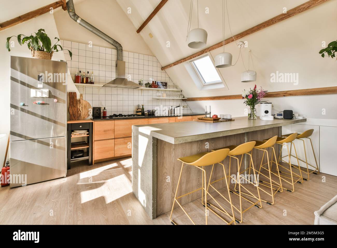 Eine Küche mit Holzfußboden und weißen Fliesen an den Wänden, zwei gelbe Hocker sind vor der Theke Stockfoto