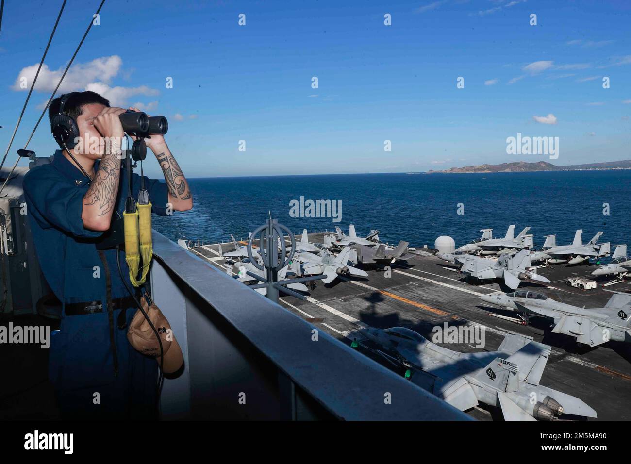 MANILA BAY, Philippinen (25. März 2022) Operations Specialist 2. Class Nicholas Gonzales, aus Cotulla, Texas, steht auf dem Hafenaussichtspunkt, während der Flugzeugträger der Nimitz-Klasse USS Abraham Lincoln (CVN 72) für einen planmäßigen Hafenbesuch in Manila Bay, Philippinen anfährt. Die Abraham Lincoln Strike Group befindet sich in einem geplanten Einsatz im US-7.-Flottenbereich, um die Interoperabilität durch Allianzen und Partnerschaften zu verbessern und gleichzeitig als einsatzbereite Truppe zur Unterstützung einer freien und offenen Region Indo-Pacific zu fungieren. Stockfoto