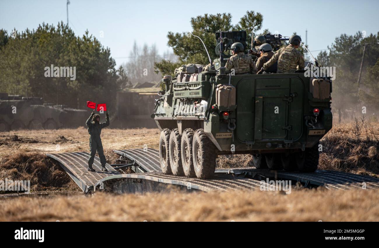 Ein polnischer Soldaten der Landstreitkräfte leitet die USA Soldaten, die dem 1. Bataillon, dem 185. Infanterie-Regiment, während einer nassen Lückenüberquerung am Bull Run 2022 zugeteilt wurden, eine Machtübung am Siemianowka Reservoir, Bondary, Polen, 25. März 2022. Stockfoto