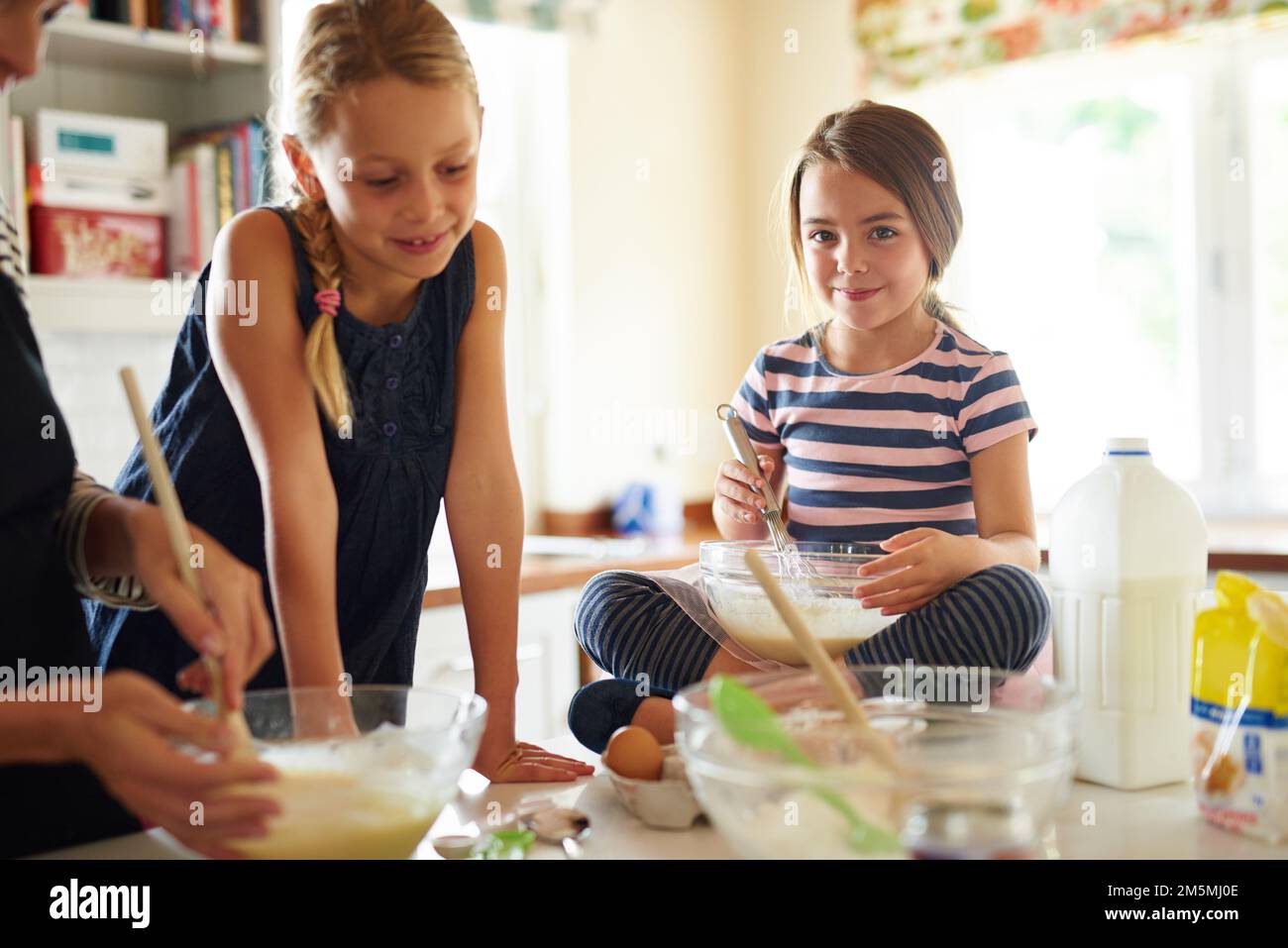 Backen macht so viel Spaß. Zwei kleine Mädchen, die mit ihrer Mutter in der Küche backen. Stockfoto