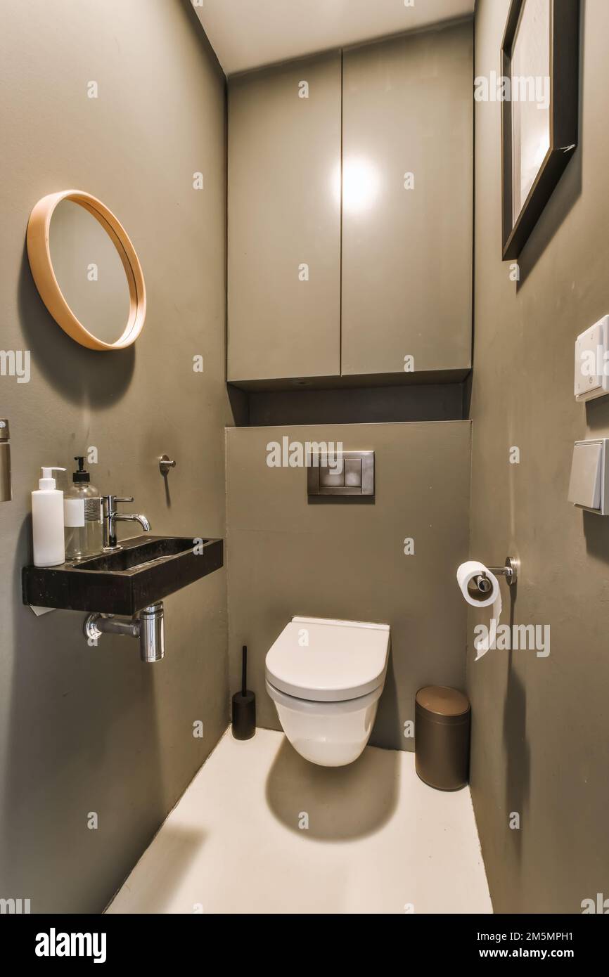 Ein Badezimmer mit Toilette, Waschbecken und Spiegel an der Wand daneben  ist ein Licht, das in der Ecke leuchtet Stockfotografie - Alamy