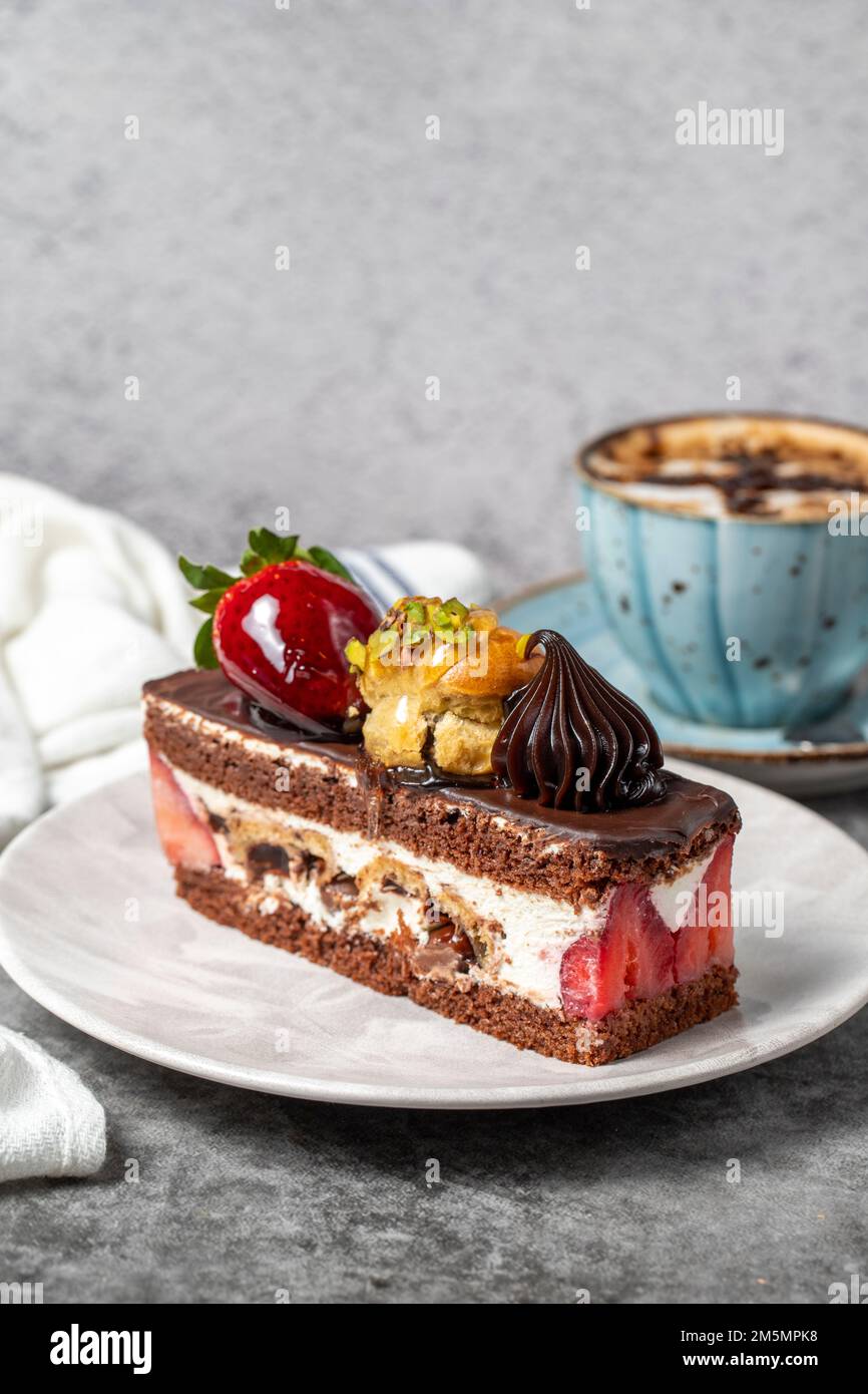 Erdbeeren- und Schokoladenkuchen auf dunklem Hintergrund. Ein Stück Schokoladenkuchen mit Kaffeetasse. Backwaren. Schließen Stockfoto