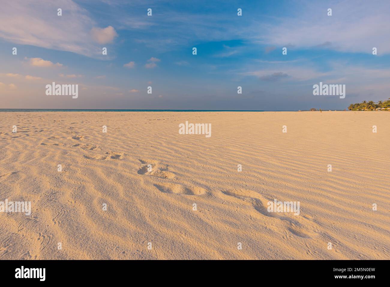 Strandhintergrund mit Fußabdrücken in Sandnaht. Konzept für Reiseurlaub. Inspirierender entspannender Strand, Wellen und Fußabdrücke bei Sonnenuntergang Stockfoto