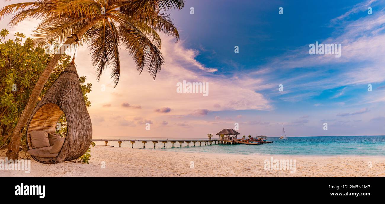 Tropisches Sonnenuntergang-Strandpanorama als Sommerlandschaft mit entspannender Strandschaukel oder Hängematte auf Kokospalmen, weißem Sand und ruhigem Strandbanner Stockfoto