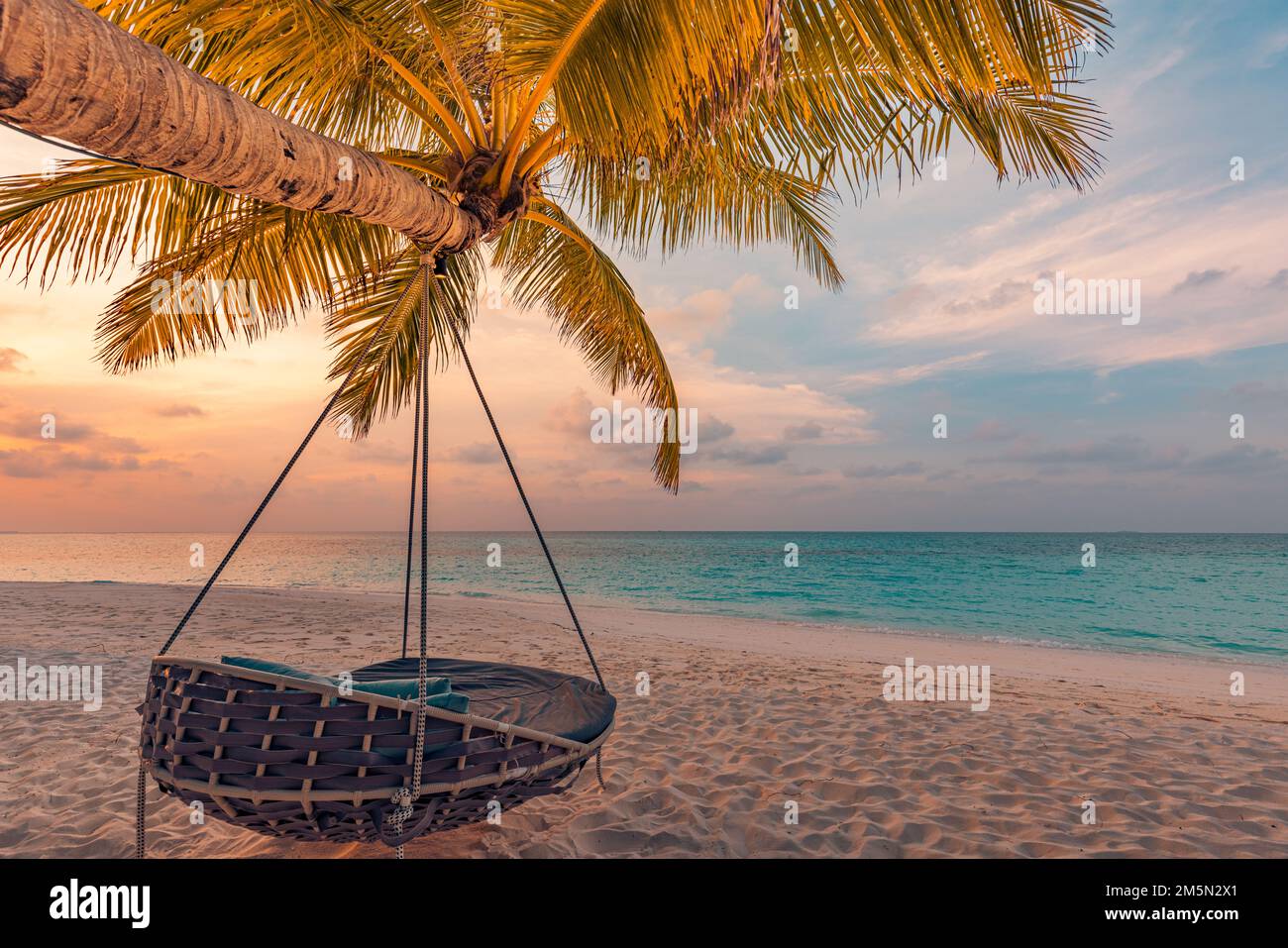 Tropisches Sonnenuntergang-Strandpanorama als Sommerlandschaft mit entspannender Strandschaukel oder Hängematte auf Kokospalmen, weißem Sand und ruhigem Strandbanner Stockfoto