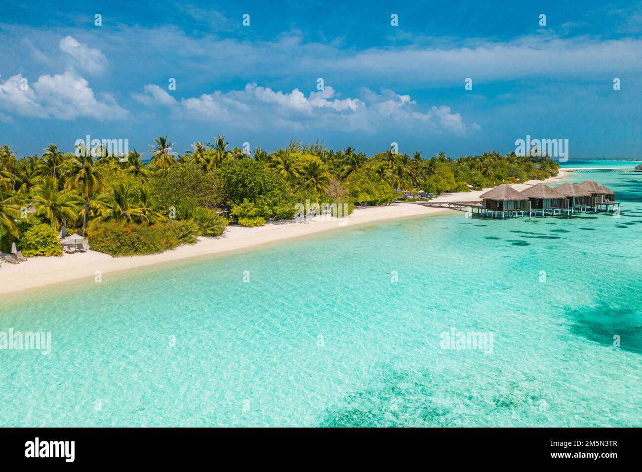 Perfekte Luftlandschaft, luxuriöses tropisches Resort mit Wasservillen. Wunderschöner Inselstrand, Palmen, sonniger Himmel. Fantastische Aussicht auf die Malediven Stockfoto