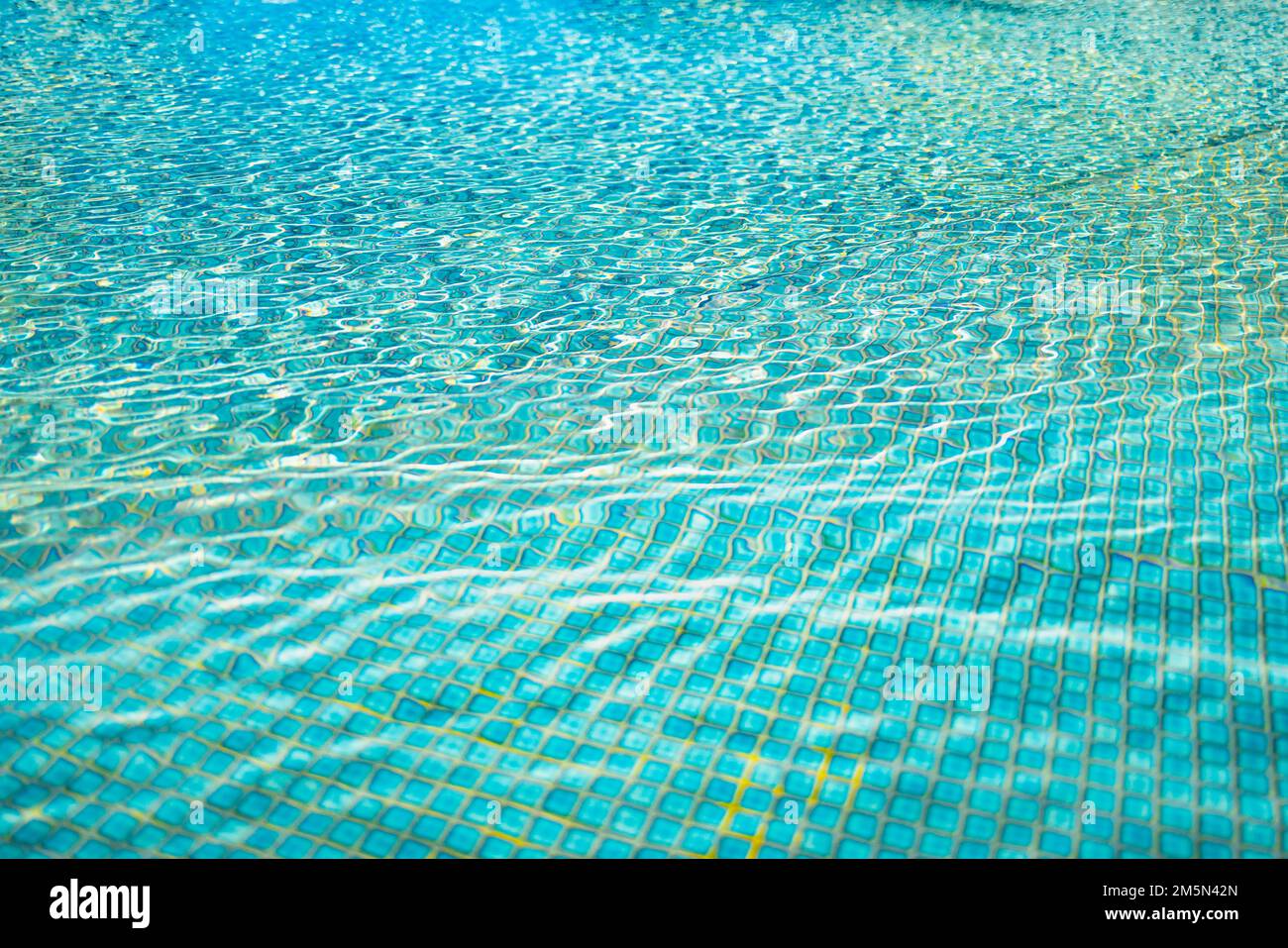 Wunderschöner entspannender Swimmingpool Wasser Sonnenreflexion Hintergrund. Hintergrund mit gewellter Wasserstruktur, natürliches Sonnenlicht. Abstrakte künstlerische Wasseroberfläche Stockfoto