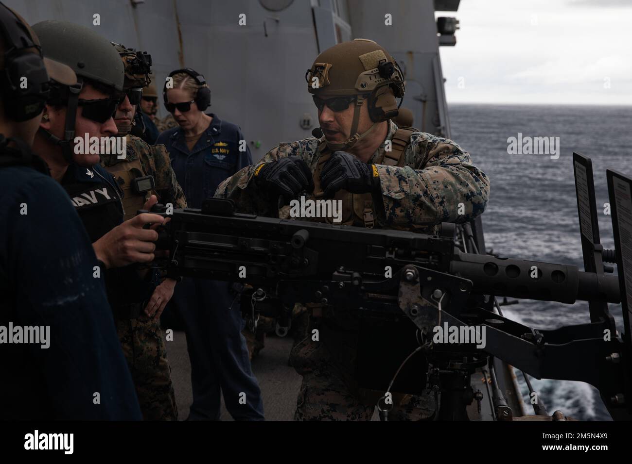 USA Marinekorps Gunnery Sergeant Charles Johnson, ein Platoon Commander der Echo Company, Bataillon Landing Team 2/6, 22. Marine Expeditionary Unit, erteilt Anweisungen und Feedback an die USA Navy Matrosen, während sie einen Maschinengewehrstand an Bord eines Amphibienschiffs der San Antonio-Klasse USS Arlington (LPD 24), 28. März 2022, ausführen. Arlington und 22. Marine Expeditionary Unit sind auf einem geplanten Einsatz unter dem Kommando und der Kontrolle der Task Force 61/2 in den USA Sechster Flottenbereich. Stockfoto
