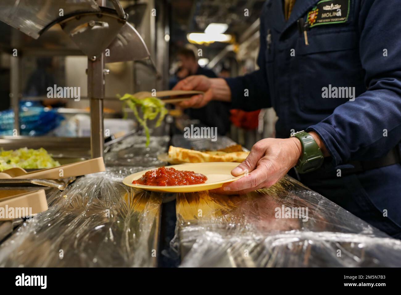 220329-N-HK187-1004 ATLANTISCHER OZEAN (29. März 2022) – Matrosen, die der Arleigh-Burke-Klasse-Guided-Missile Destroyer USS The Sullivans (DDG 68) zugeteilt wurden, bereiten ab dem ‚Taco Tuesday‘, dem 29. März, ihre eigenen Platten vor. Die Sullivans werden in das europäische Operationstheater entsandt und nehmen an einer Reihe von maritimen Aktivitäten zur Unterstützung der USA Teil Sechste Flotte und NATO-Alliierten. Stockfoto
