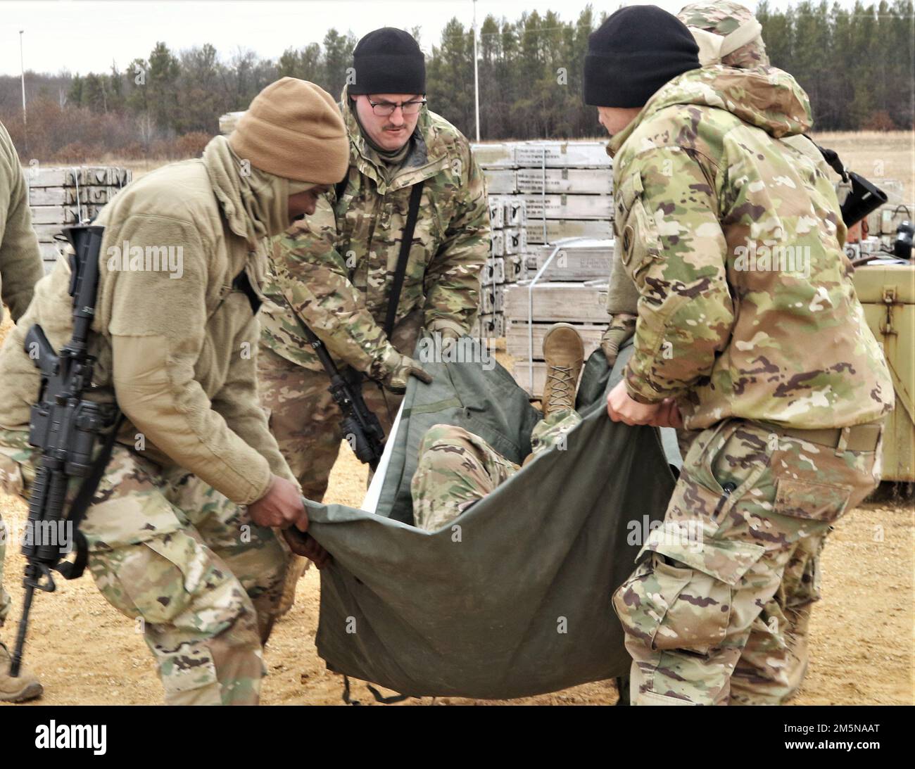 USA Army Reserve Sergeant Terrell Brooks, Left, zugewiesen zur 395. Ordnance Company, 103. Expeditionary Sustainment Command, 79. Theater Sustainment Command, Neenah, Wisconsin, Nicholas Evert demonstriert während der jährlichen Schulung des Unternehmens in Fort McCoy, Wisconsin, am 29. März 2022, wie sie mit einer Plane an einem Munitionslieferort einen anderen "verletzten" Soldat SPC. Brandon Johnson transportieren konnten. Diese individuelle und kollektive Schulung bereitete das Unternehmen darauf vor, seine Bereitschaft zur Vorbereitung der Mobilisierung in Fort Hood, Texas, unter Beweis zu stellen. Stockfoto