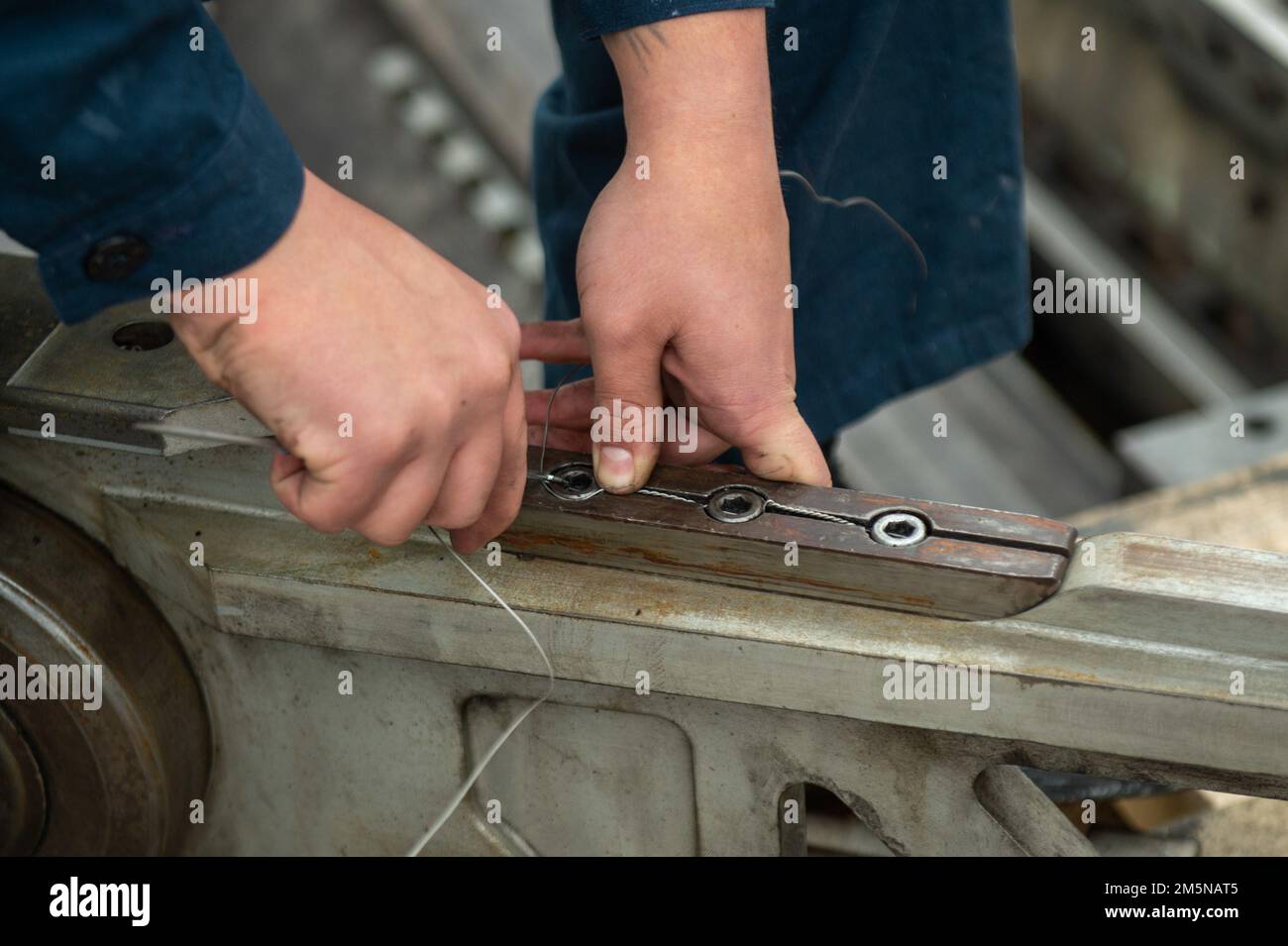 220329-N-SI601-2002 YOKOSUKA, Japan (29. März 2022) Aviation Boatswain’s Mate (Equipment) Airman Michael Maile aus Santa Fe, New Mexico, ersetzt das Sicherheitsseil eines Katapult-Shuttles in den USA Der einzige vorwärtsgesetzte Flugzeugträger der Navy USS Ronald Reagan (CVN 76). Der Sicherheitsdraht muss regelmäßig an den Katapult-Shuttles ausgetauscht werden, um die Integrität des Katapults zu erhalten. Ronald Reagan, das Flaggschiff der Carrier Strike Group 5, stellt eine kampfbereite Truppe bereit, die die Vereinigten Staaten schützt und verteidigt und Bündnisse, Partnerschaften und kollektive maritime Interessen in unterstützt Stockfoto