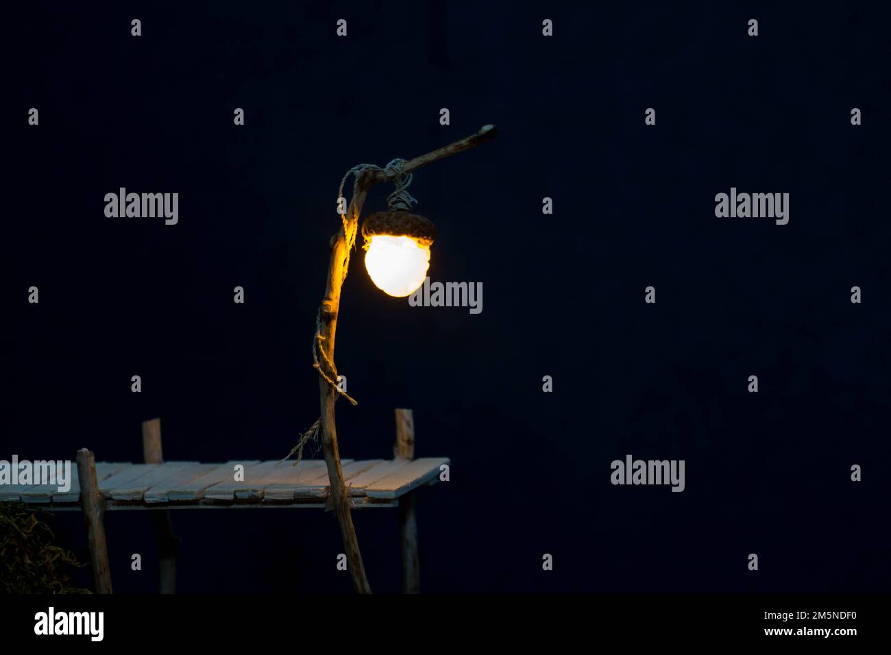Märchenhaftes Holzdock bei Nacht, beleuchtet von einer Eichellaterne, die mit einer Nesselschnur aufgehängt wurde Stockfoto