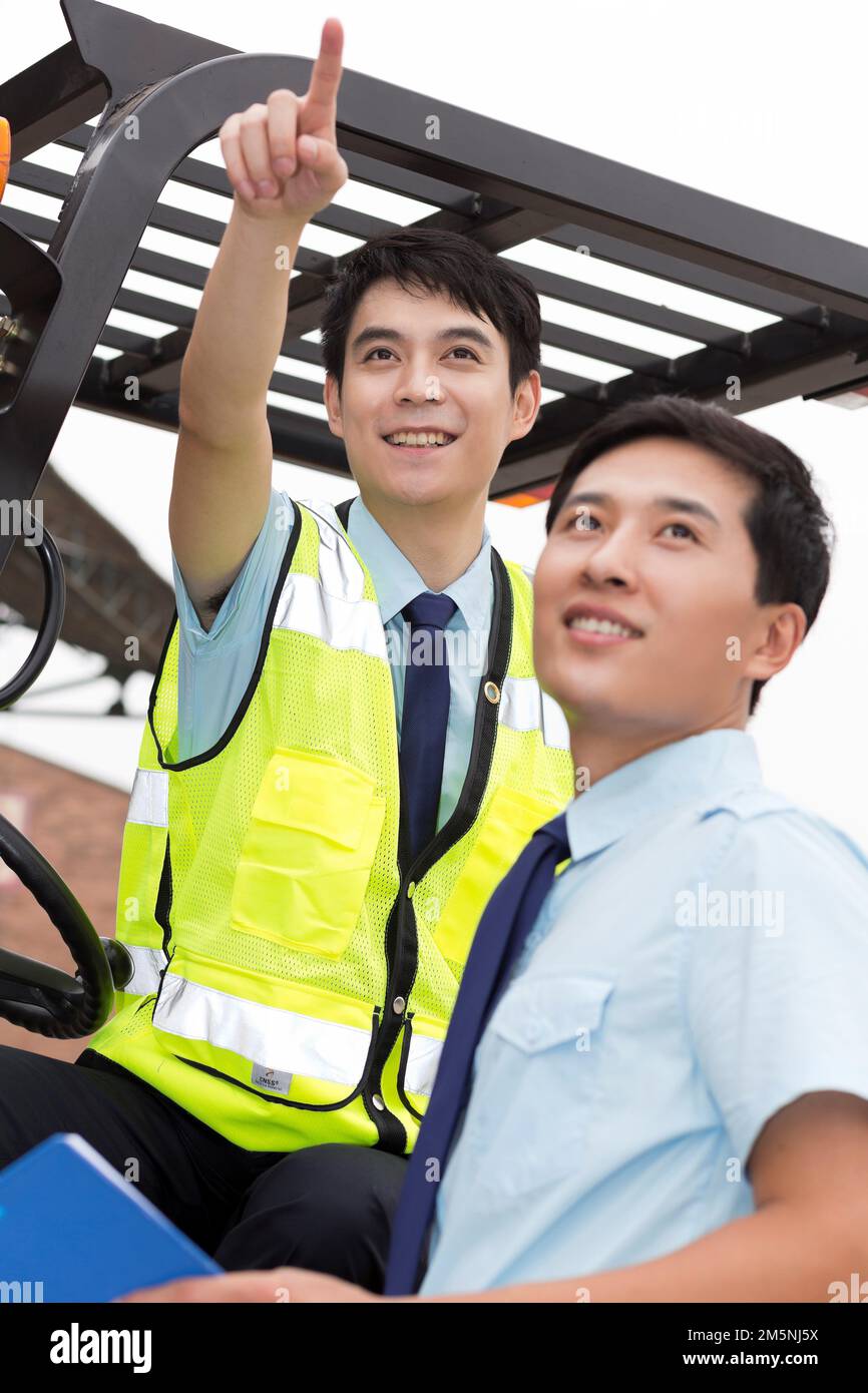 Das Management des Logistiklagers spricht mit dem Fahrer eines Gabelstaplers Stockfoto