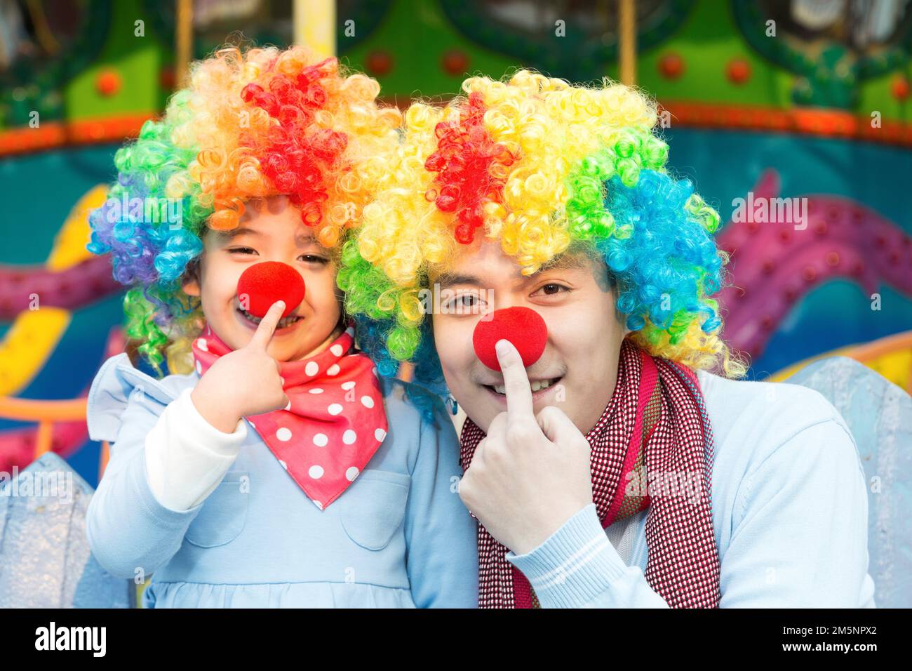 Glücklicher Vater und Clown im Vergnügungspark zum Spielen Stockfoto
