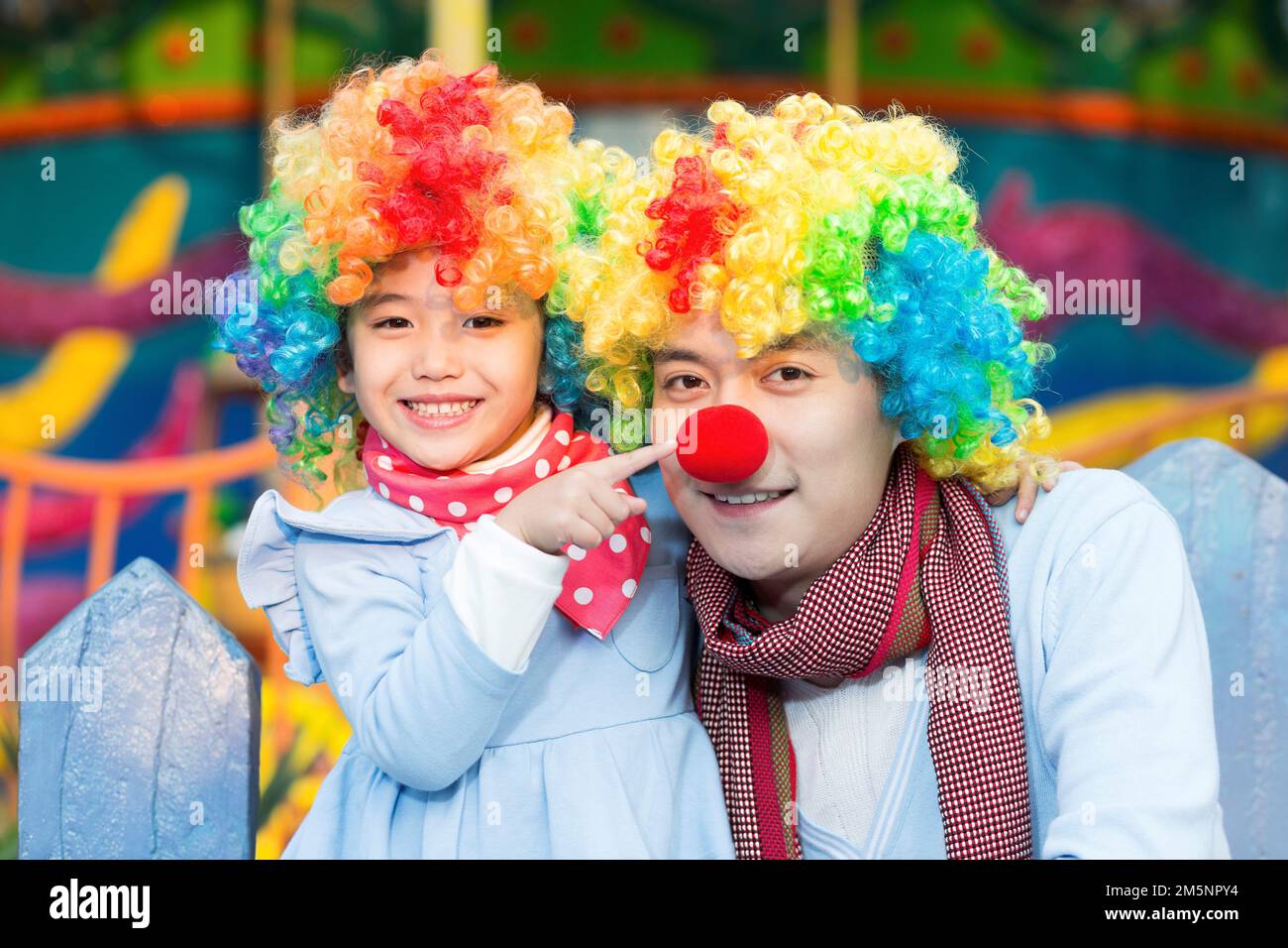 Glücklicher Vater und Clown im Vergnügungspark zum Spielen Stockfoto