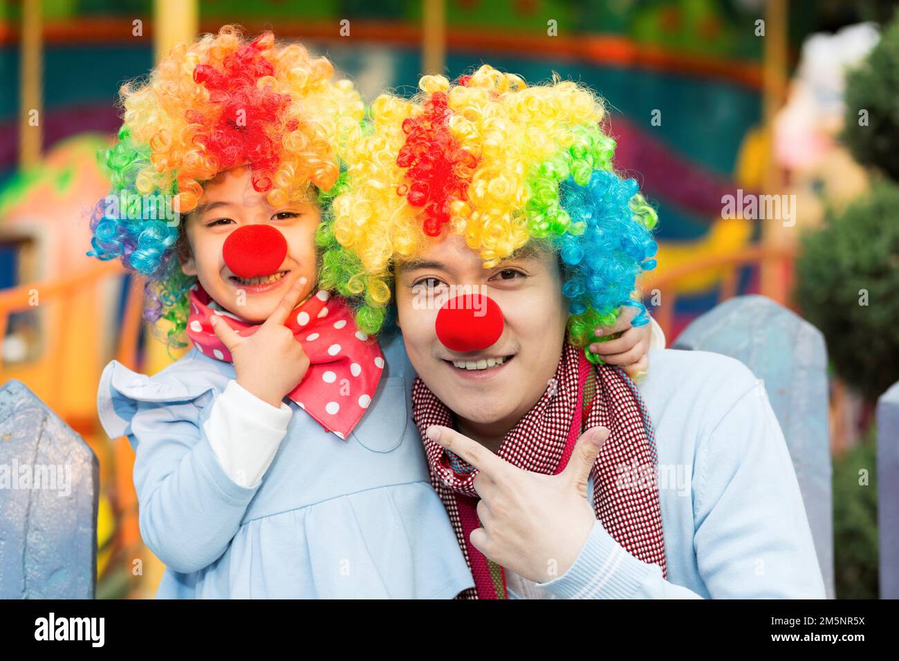 Glücklicher Vater und Clown im Vergnügungspark zum Spielen Stockfoto