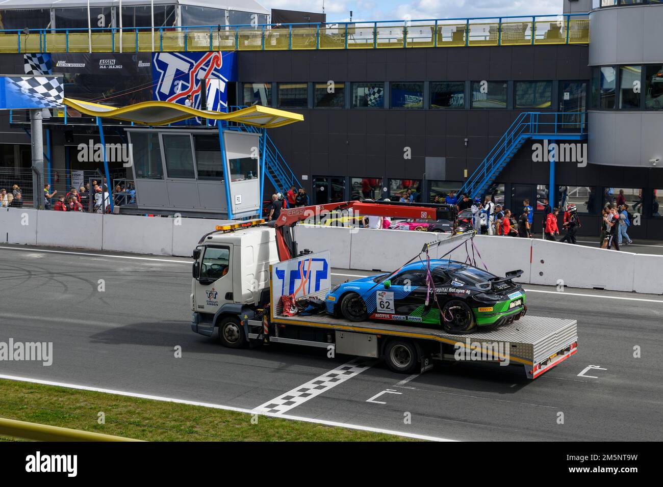 Der Abschleppwagen transportiert den beschädigten Rennwagen Porsche Cayman GT4 über die Rennstrecke zur Ziellinie nach einem Rennunfall, TT Circuit Assen Stockfoto