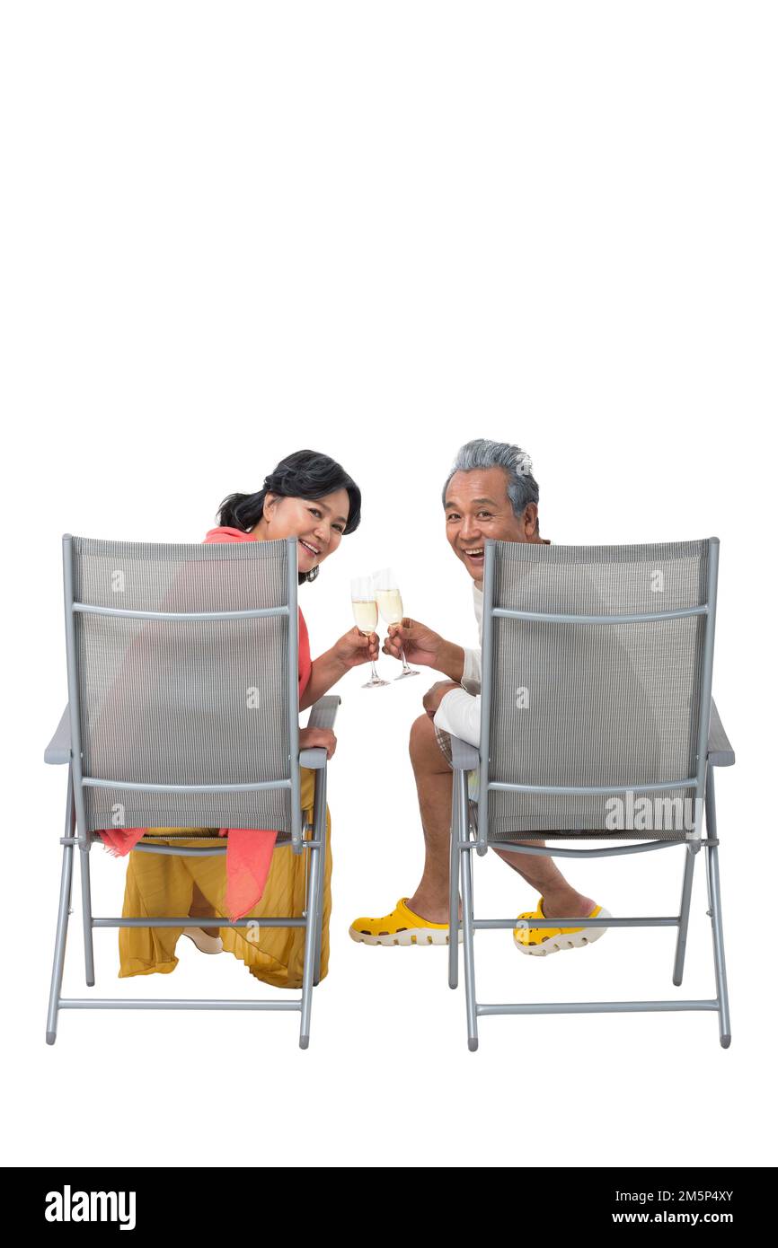 Glückliches älteres Paar, das auf einem Liegestuhl sitzt, trinkt Champagner Stockfoto