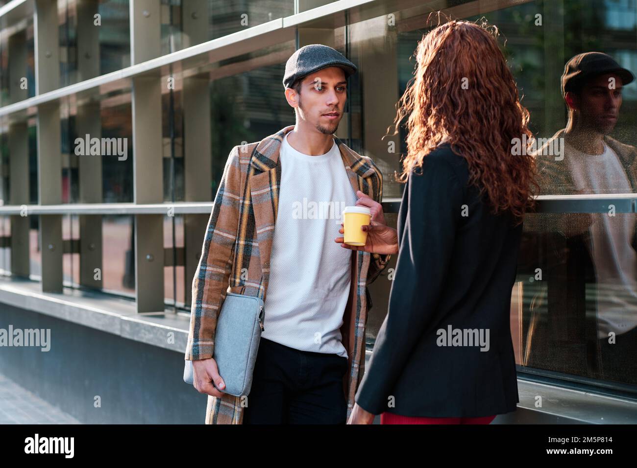 Ein Mann, der vor dem Bürogebäude mit einer Kollegin spricht. Stockfoto