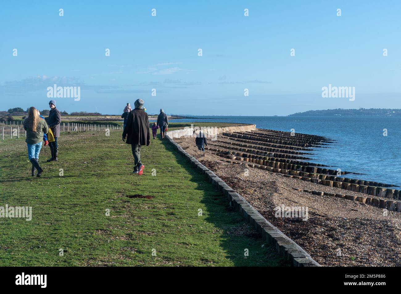 Park Shore Beach in der Nähe von Beaulieu, Hampshire, England, Großbritannien, an einem sonnigen Wintertag, mit Menschen und Familien für einen Spaziergang Stockfoto