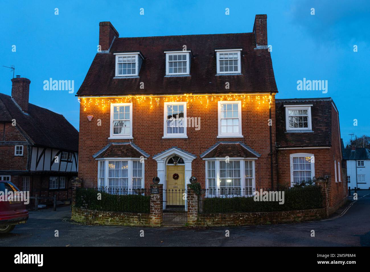 Little Court in Odiham Village, Hampshire, England, Großbritannien, ein denkmalgeschütztes Gebäude im Bury, das im Dezember in der Abenddämmerung mit Weihnachtslichtern dekoriert ist Stockfoto