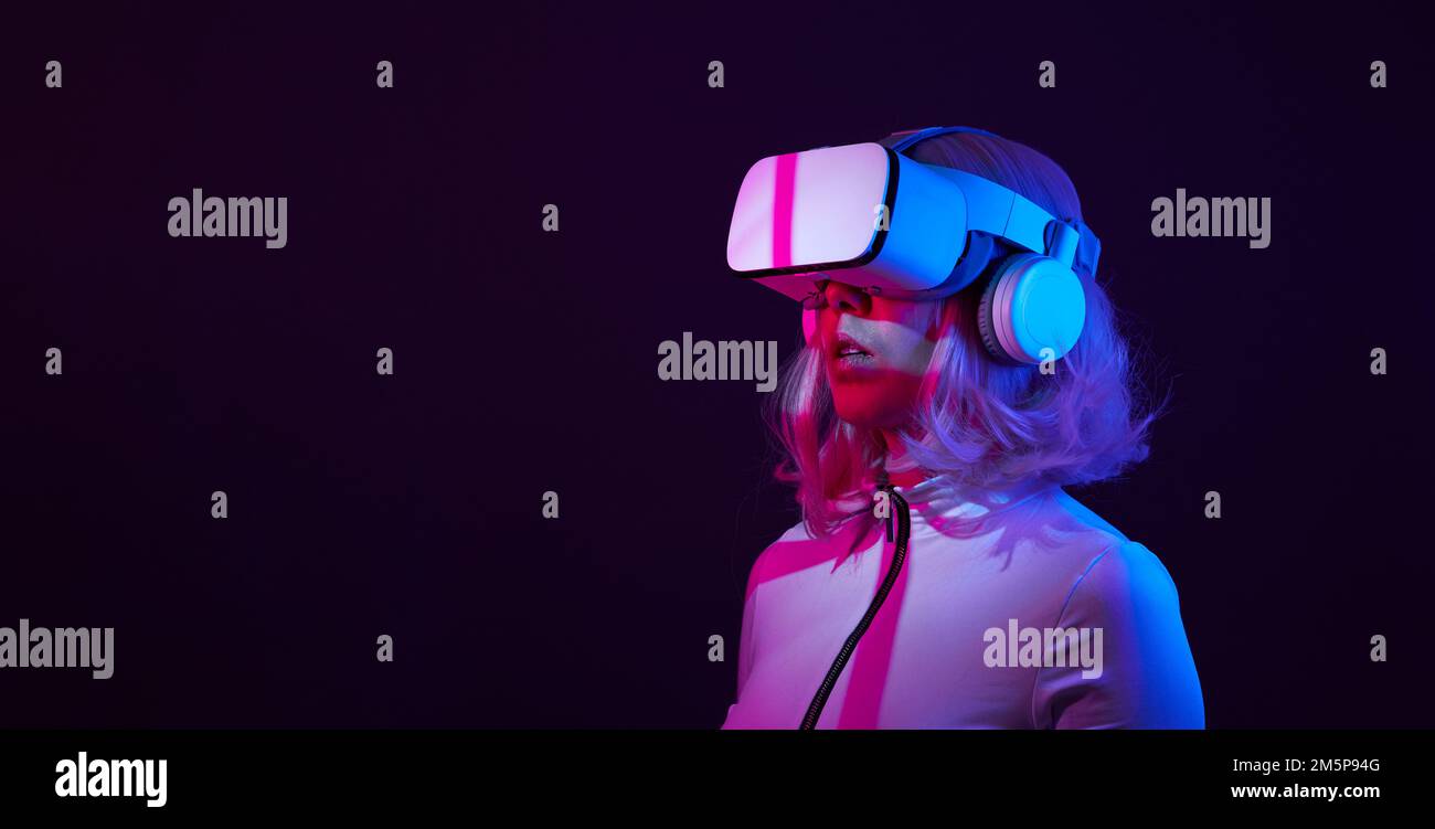 Eine Frau in Virtual-Reality-Brille in Neonfarben. Das Konzept der digitalen Technologie für Metaversum und Unterhaltung der Zukunft. Stockfoto