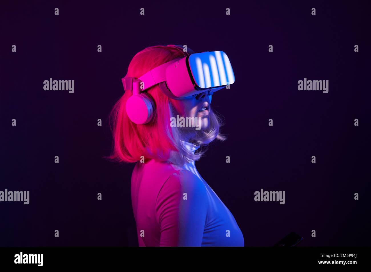 Eine Frau in Virtual-Reality-Brille in Neonfarben. Das Konzept der digitalen Technologie für Metaversum und Unterhaltung der Zukunft. Stockfoto