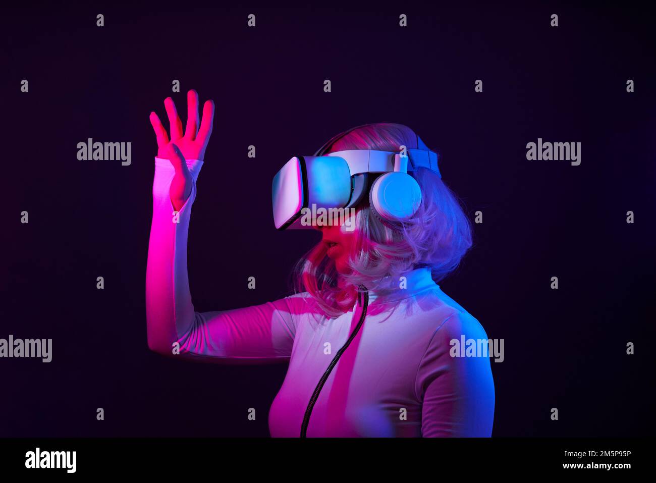 Eine Frau in Virtual-Reality-Brille in Neonfarben. Das Konzept der digitalen Technologie für Metaversum und Unterhaltung der Zukunft. Stockfoto