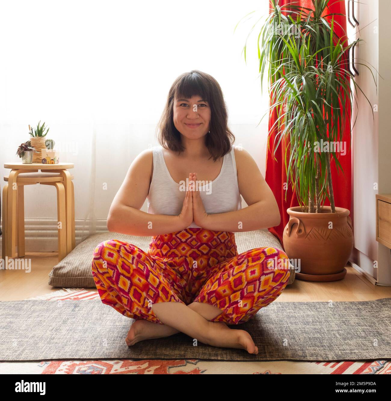 Junge weiße Frau, die zu Hause Yoga praktiziert Stockfoto
